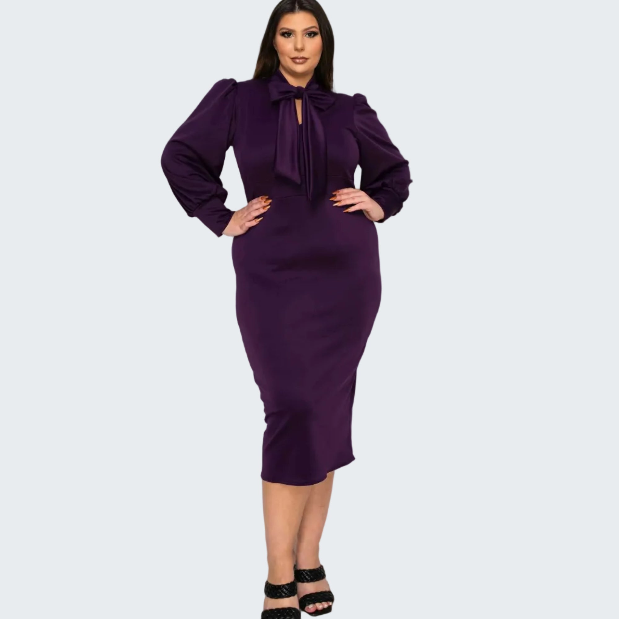 A woman modeling a fitted knee-length purple dress with long balloon sleeves, a large bow at the neckline, and a keyhole cutout, paired with black strappy heels against a plain white background.