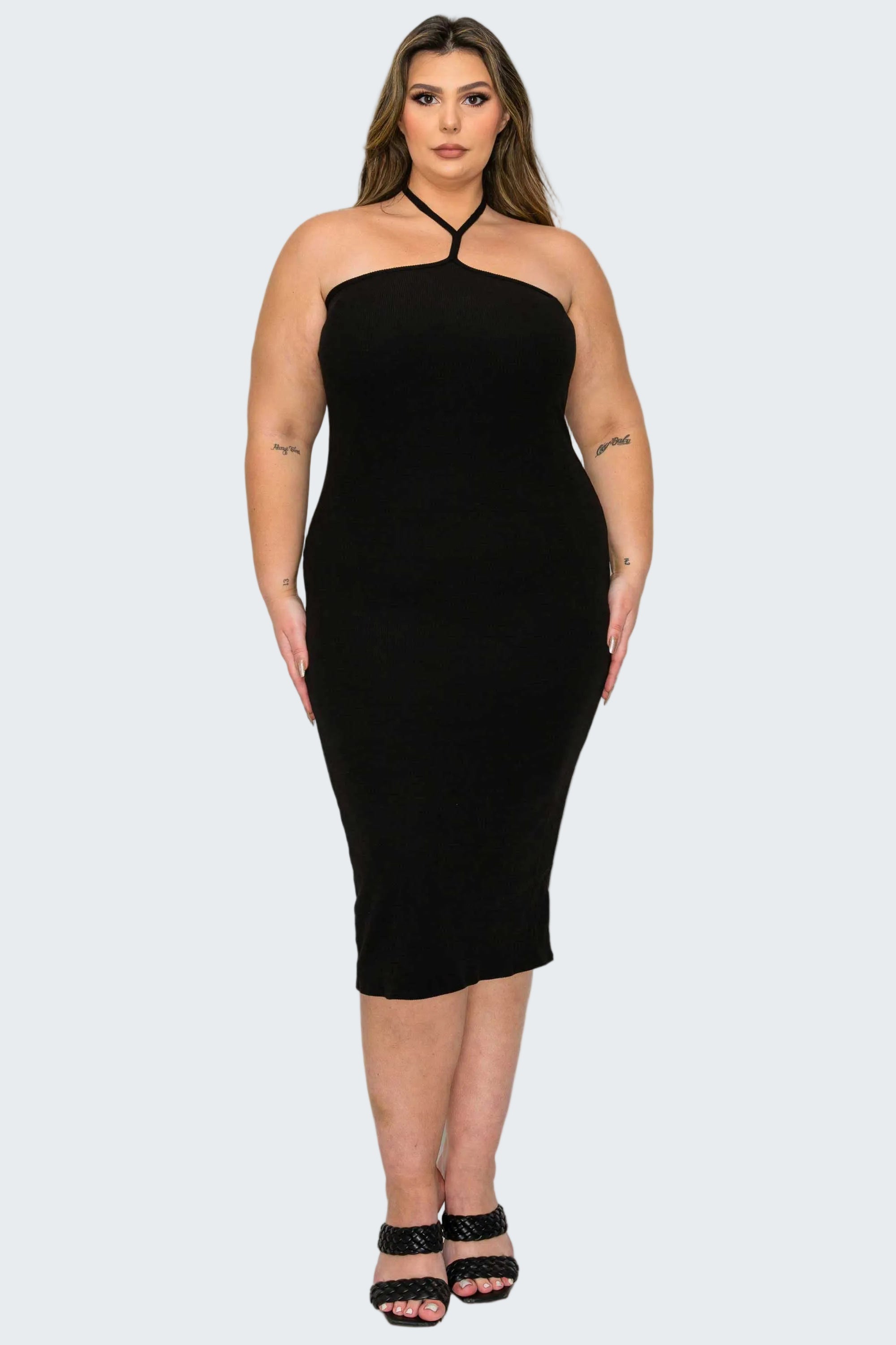 A woman modeling a black halter-neck midi dress with a bodycon fit, paired with black strappy high-heeled sandals, against a plain white background.