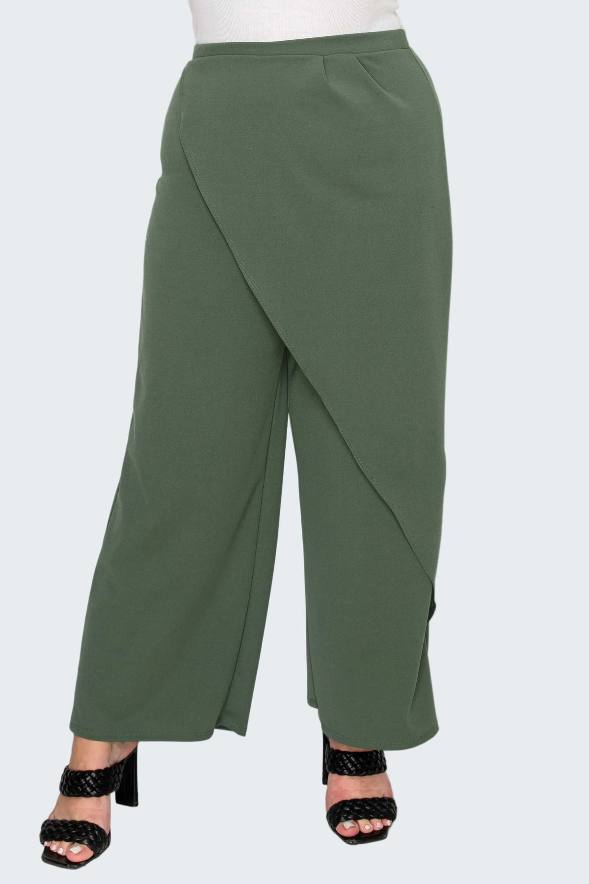 A pair of olive green wide-leg cropped pants with an asymmetrical wrap-style front, shown on a model wearing black heeled sandals against a white background.