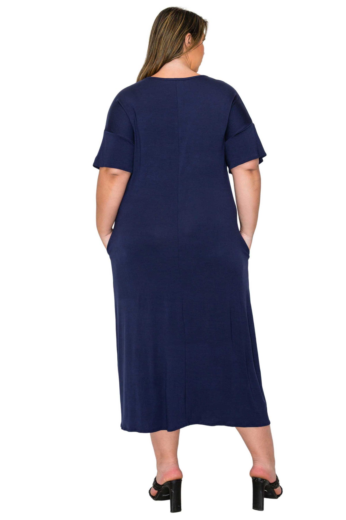 A woman viewed from the back wearing a navy blue short-sleeve midi dress with side pockets, paired with black heeled sandals, against a plain white background.