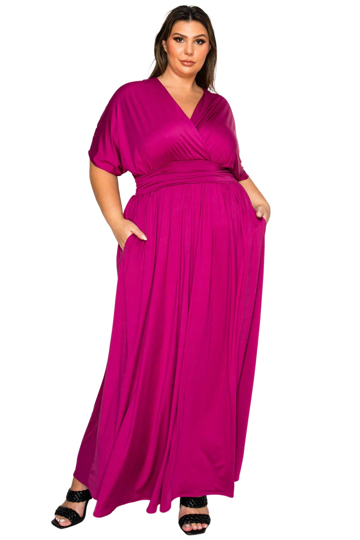 A woman modeling a magenta maxi dress with a wrap-style V-neck bodice, short flutter sleeves, side pockets, and a flowing skirt, shown against a plain white background.