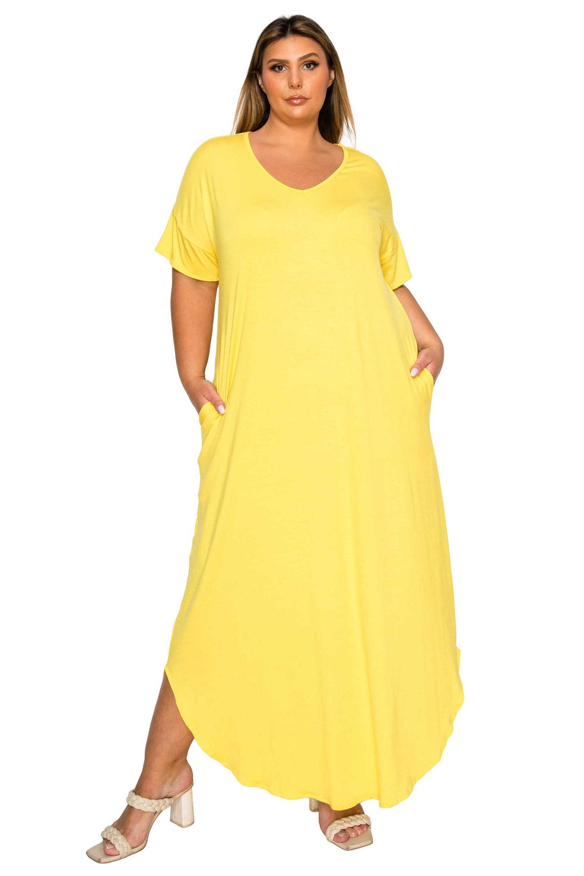 A woman modeling a bright yellow, short-sleeved maxi dress with side pockets, paired with beige heeled sandals, against a plain white background.