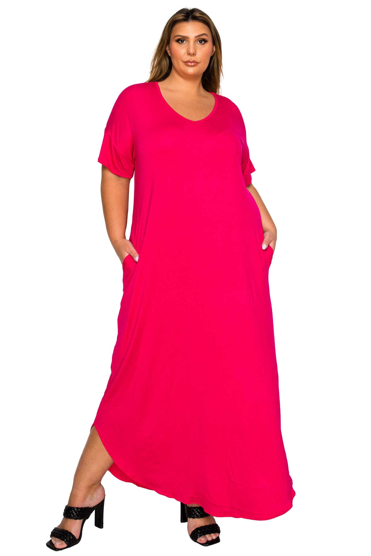 A woman modeling a bright pink short-sleeve maxi dress with side pockets, paired with black heeled sandals, against a plain white background.