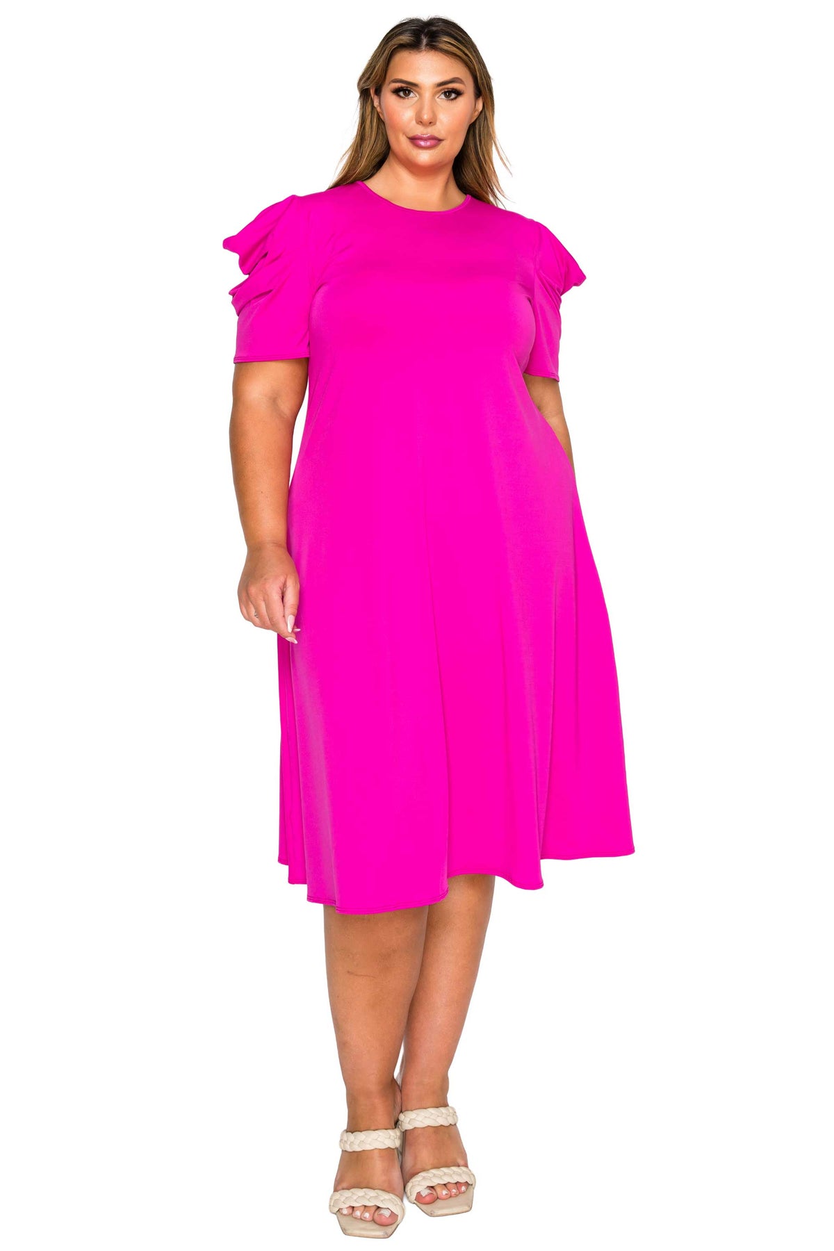 A woman modeling a bright hot pink midi dress with ruffled short sleeves and a round neckline, paired with white strappy high-heeled sandals, against a plain white background.