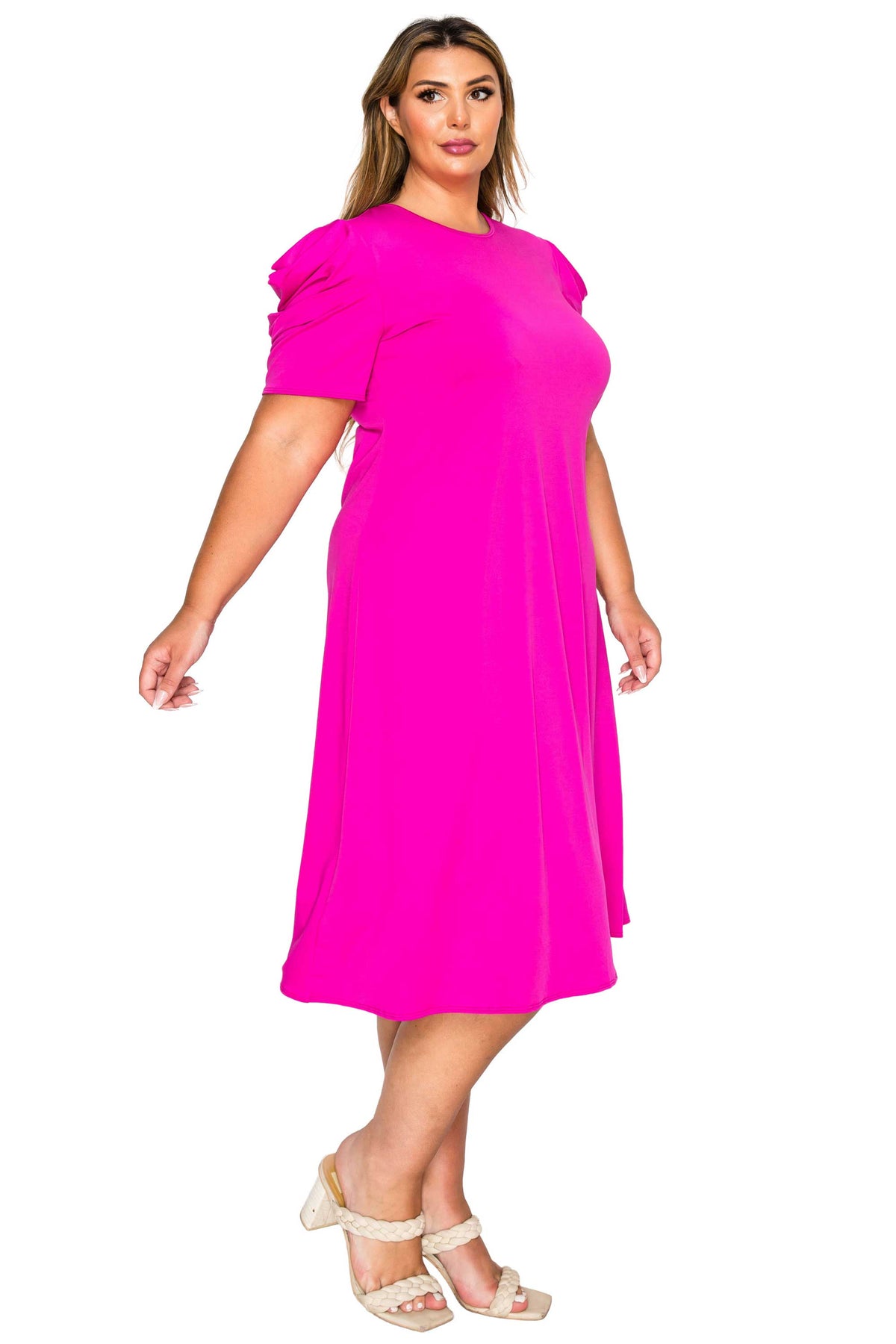 A woman modeling a bright hot pink short-sleeve midi dress with puffed shoulders, paired with beige strappy heels, against a plain white background.