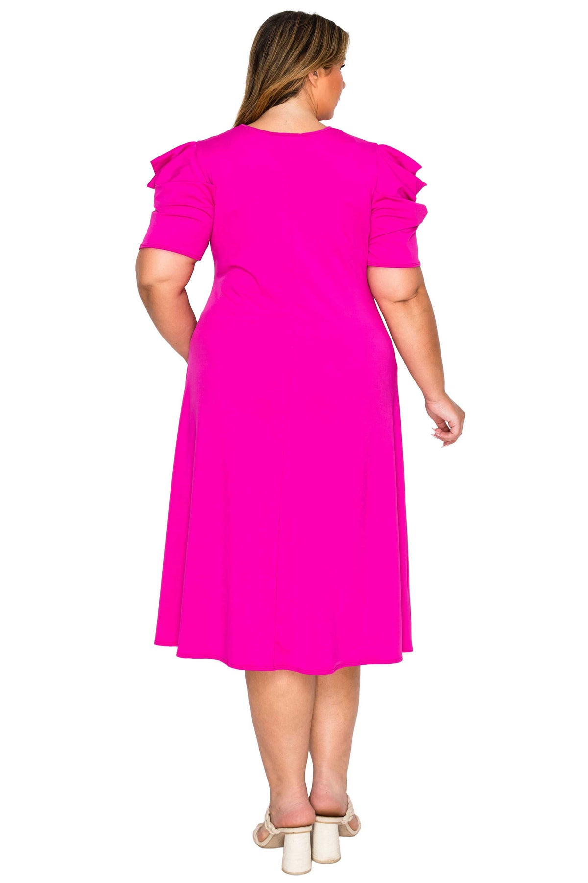 A woman viewed from the back wearing a bright hot pink midi dress with ruffled short sleeves and beige block-heel sandals, set against a plain white background.