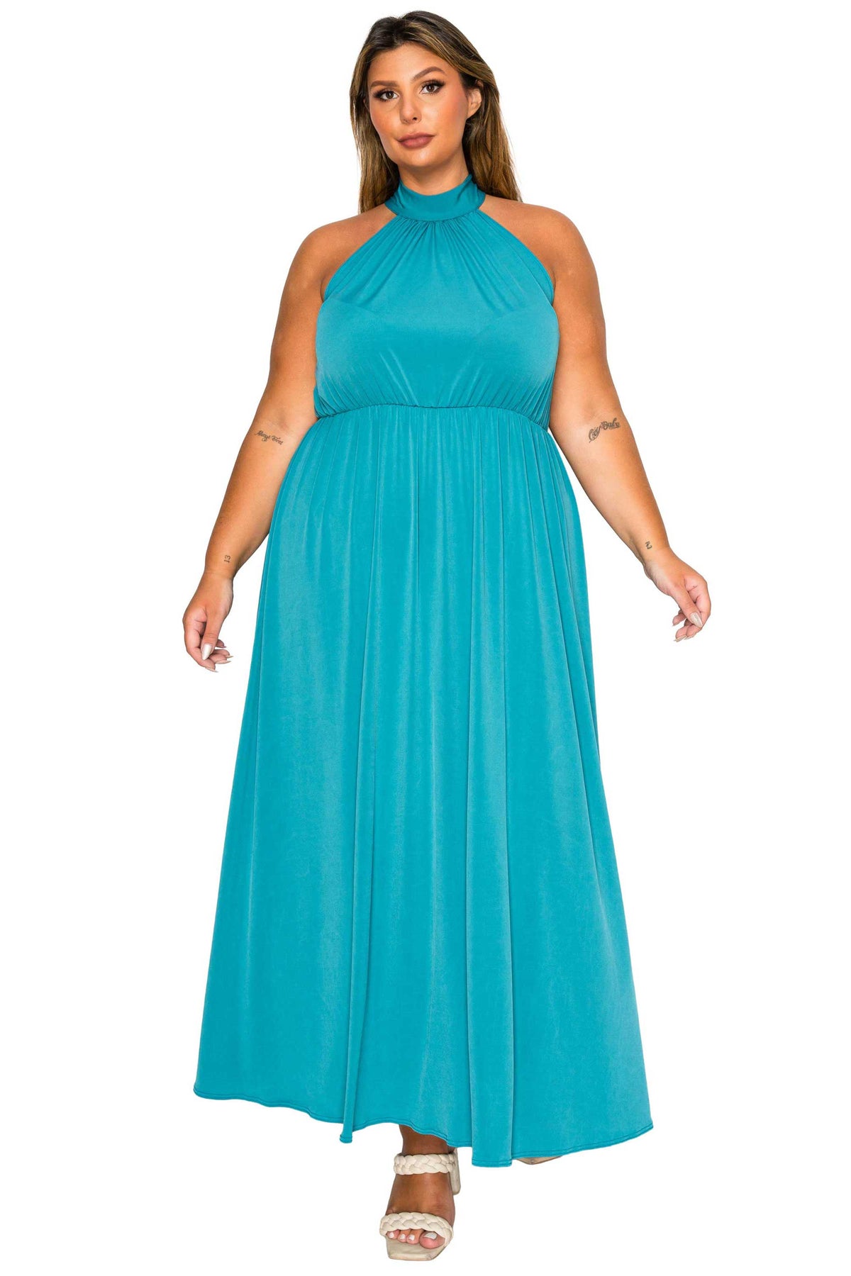 A woman modeling a sleeveless halter-neck maxi dress in a bright turquoise blue color, shown against a plain white background.