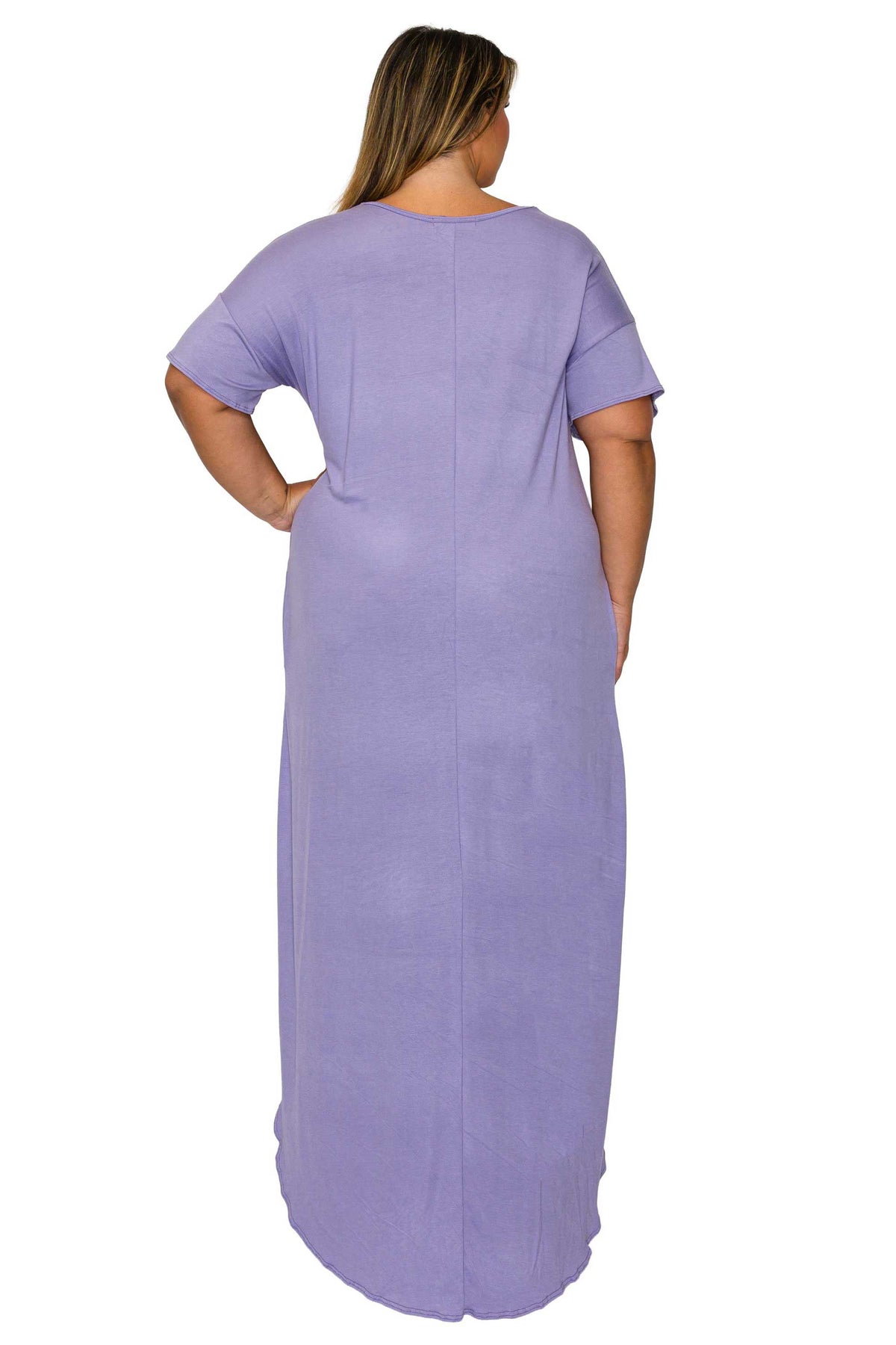 A woman viewed from the back wearing a loose, short-sleeve maxi dress in a light lavender purple color, set against a plain white background.
