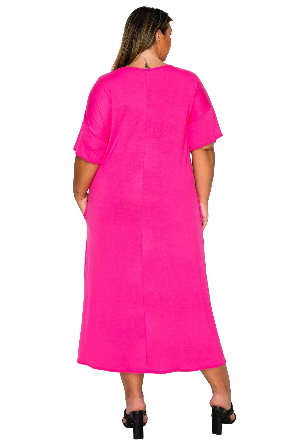 A woman viewed from the back wearing a bright hot pink short-sleeve midi dress with black heeled sandals, set against a plain white background.