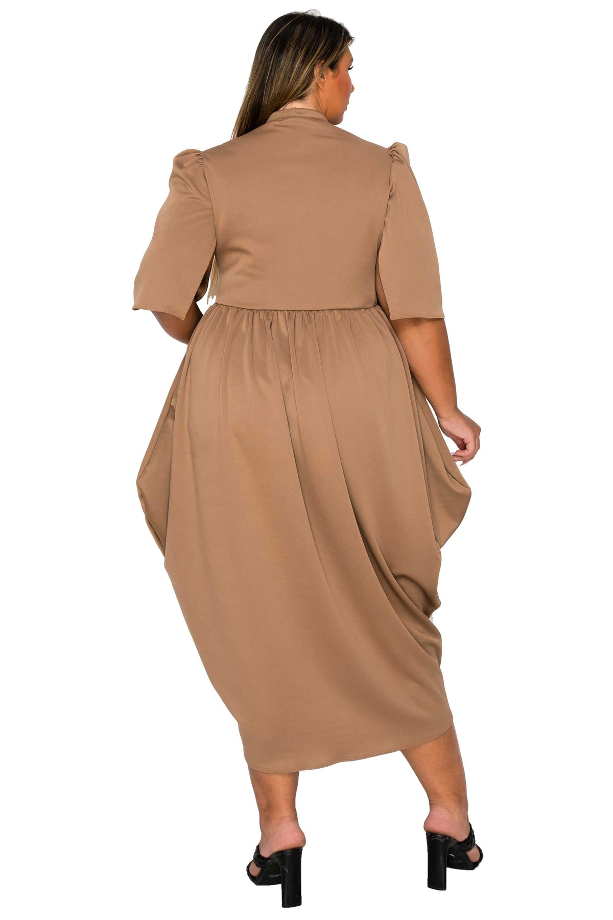 A woman shown from the back wearing a tan midi dress with short puff sleeves and black heeled sandals against a plain white background.