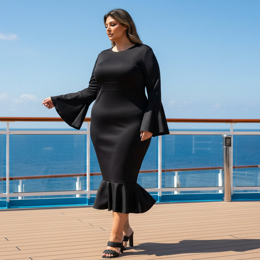 A woman modeling a black long-sleeve midi dress with flared bell sleeves and a ruffled hem, paired with black strappy heels, against a plain white background.