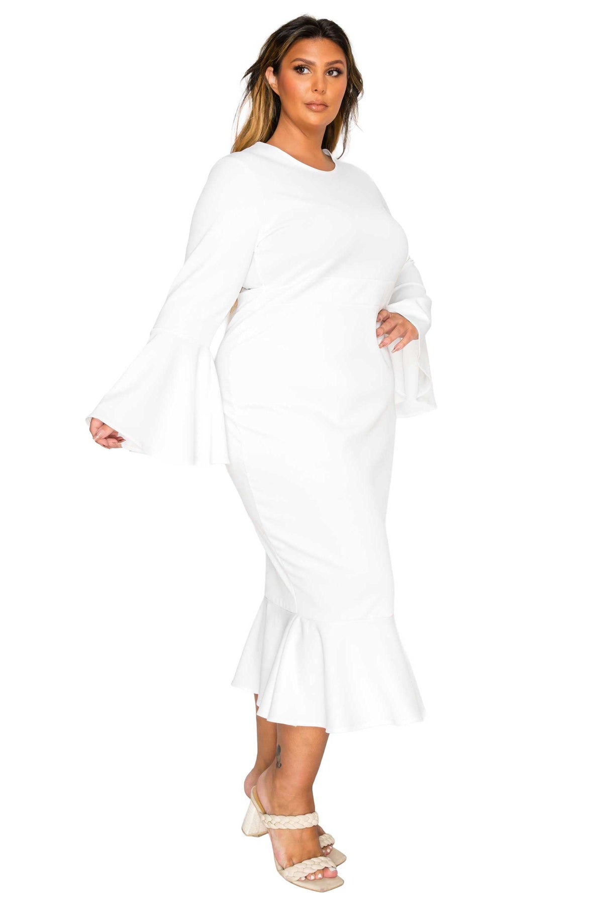 A woman modeling a white long-sleeve midi dress with flared bell sleeves and a ruffled hem, paired with beige strappy sandals against a plain white background.
