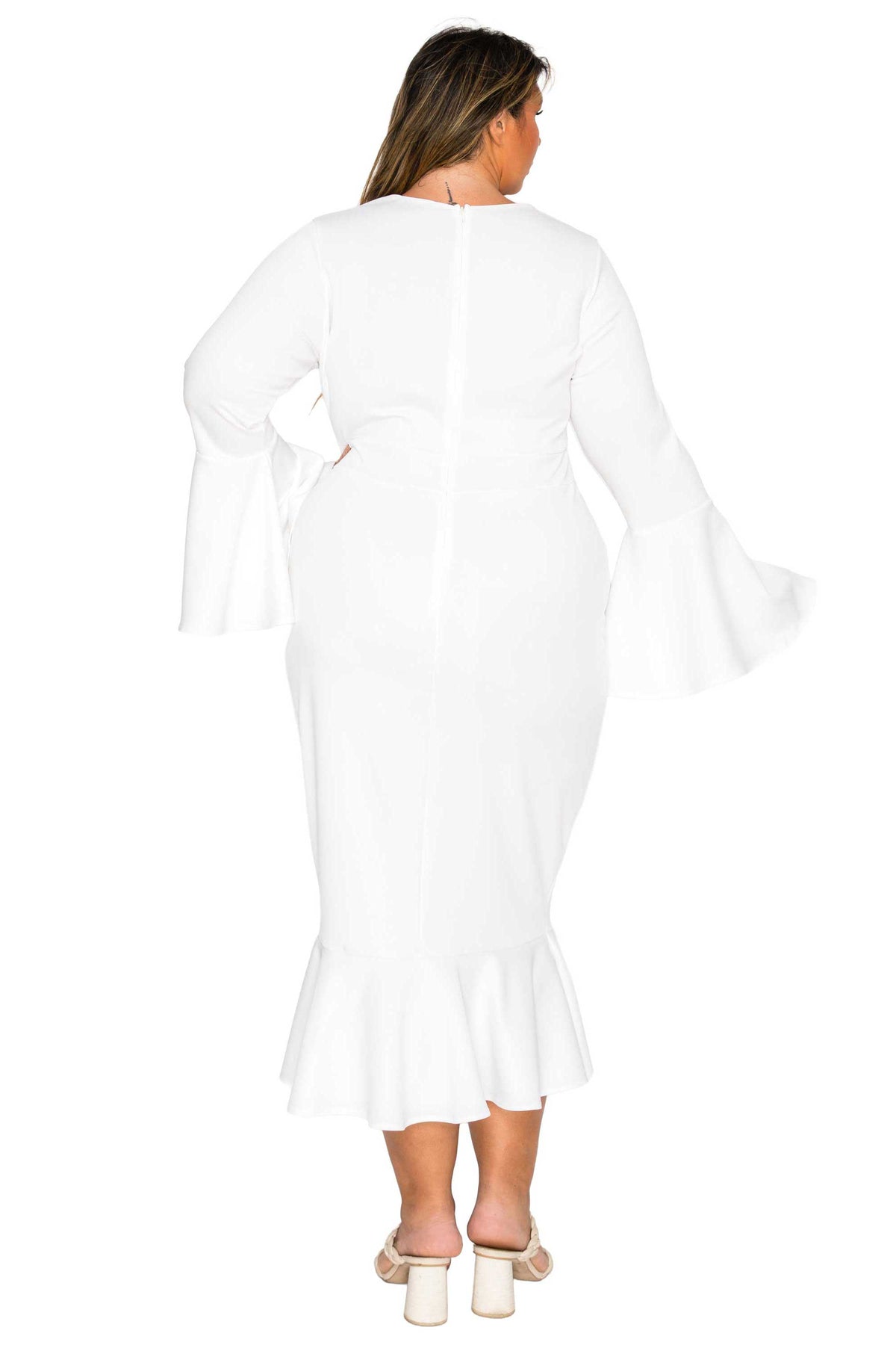 A woman viewed from the back wearing a white long-sleeve midi dress with flared bell sleeves and a ruffled hem, paired with white heeled sandals against a plain white background.