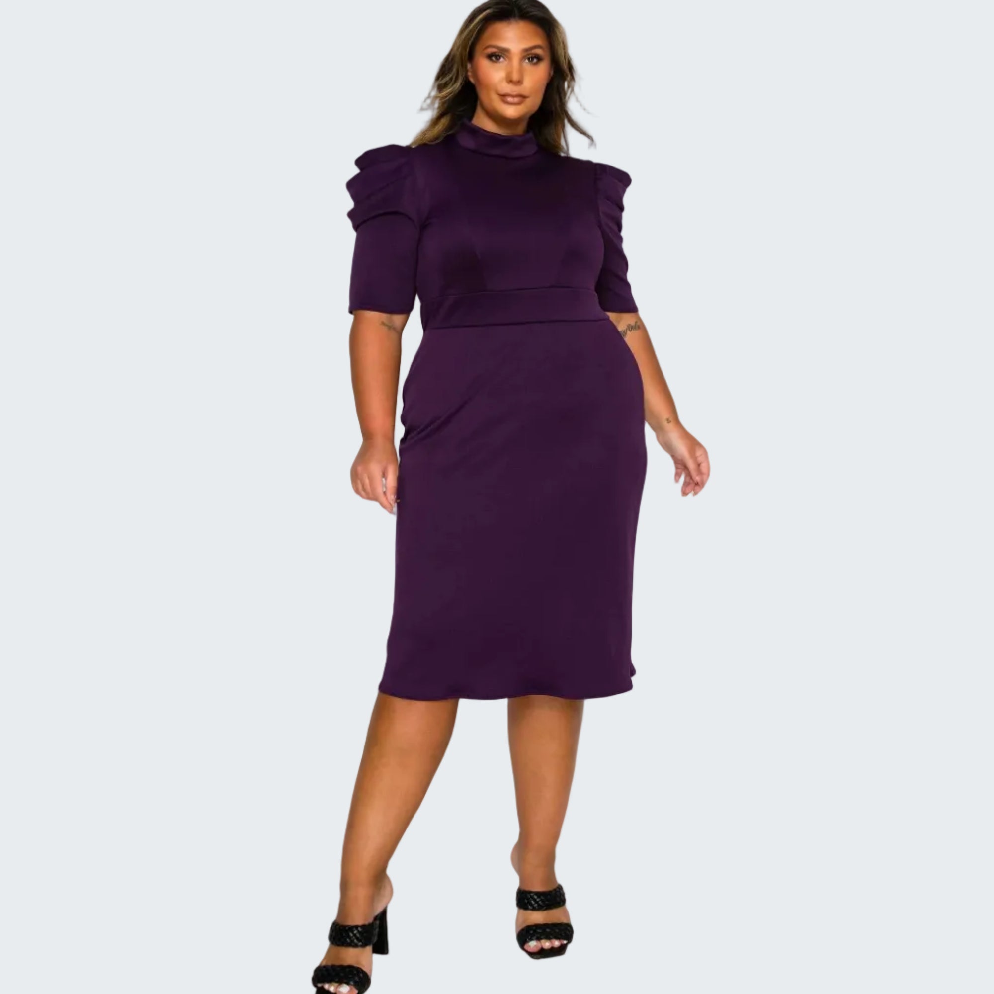 A woman modeling a deep purple midi dress with puffed short sleeves, a mock neck, and a fitted waist, paired with black heeled sandals against a plain white background.
