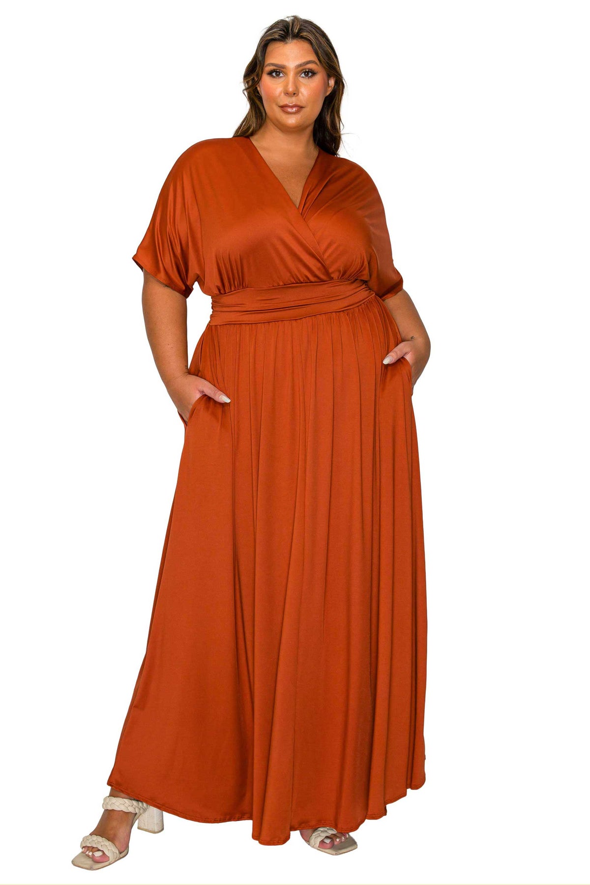 A woman modeling a rust-orange maxi dress with a wrap-style V-neck bodice, short flutter sleeves, side pockets, and a flowing skirt, shown against a plain white background.