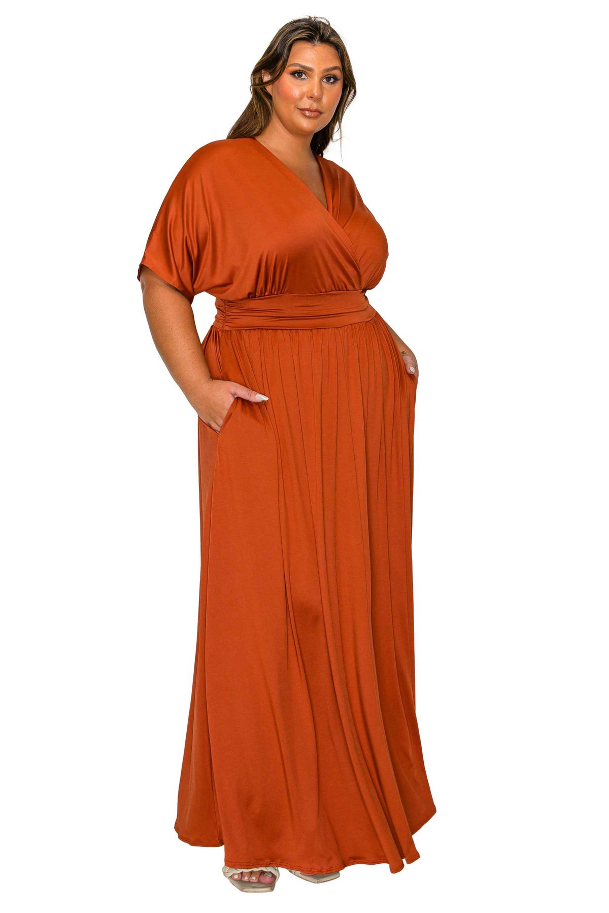 A woman modeling a rust-orange maxi dress with a V-neckline, short flutter sleeves, a matching waist tie, and side pockets, set against a plain white background.
