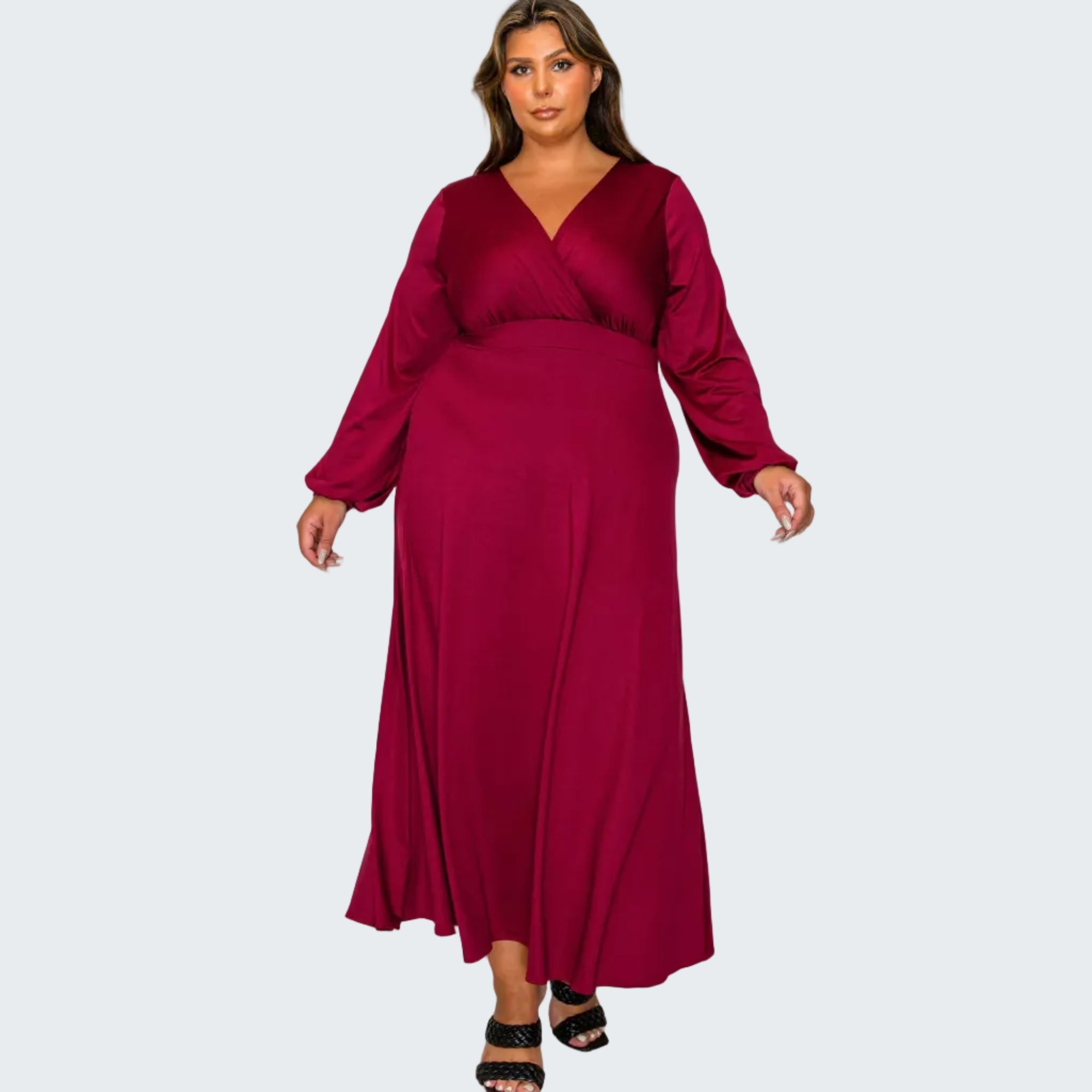 A woman modeling a long-sleeve, wrap-style maxi dress in deep burgundy against a plain white background.
