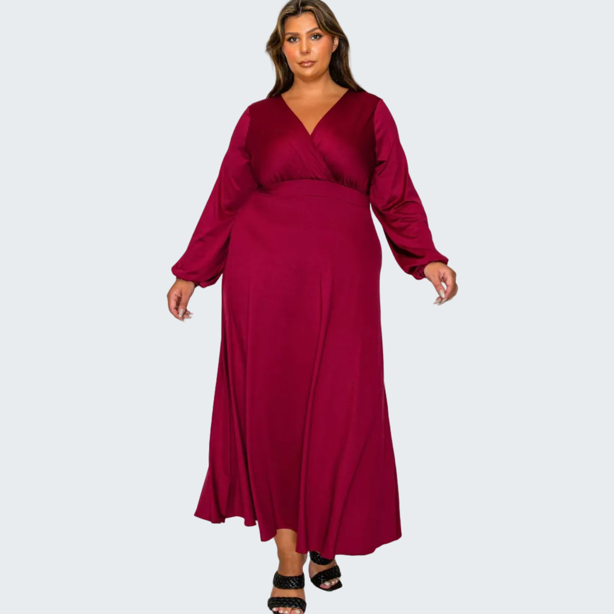 A woman modeling a long-sleeve, wrap-style maxi dress in deep burgundy against a plain white background.