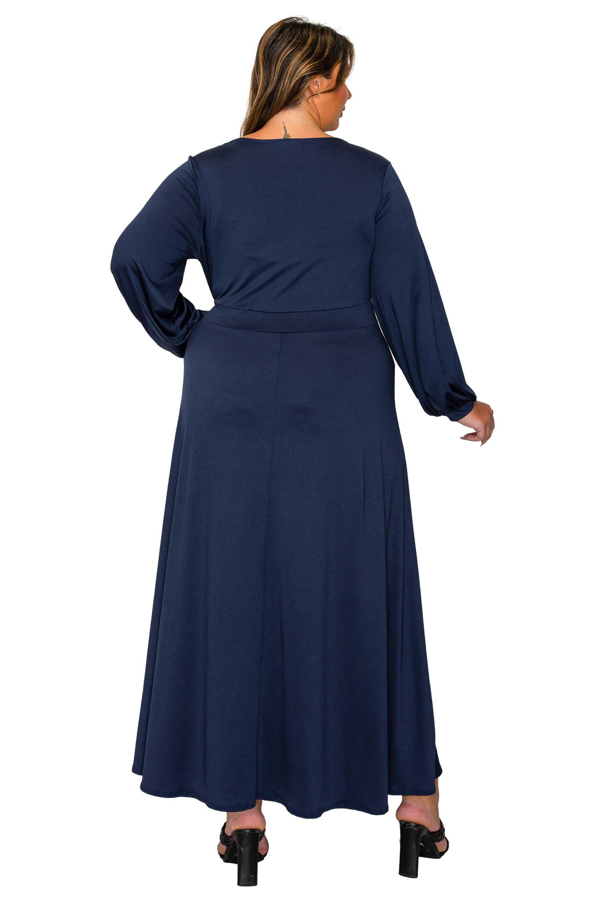 A woman viewed from the back wearing a long-sleeve navy maxi dress with a defined waist, photographed against a plain white background.
