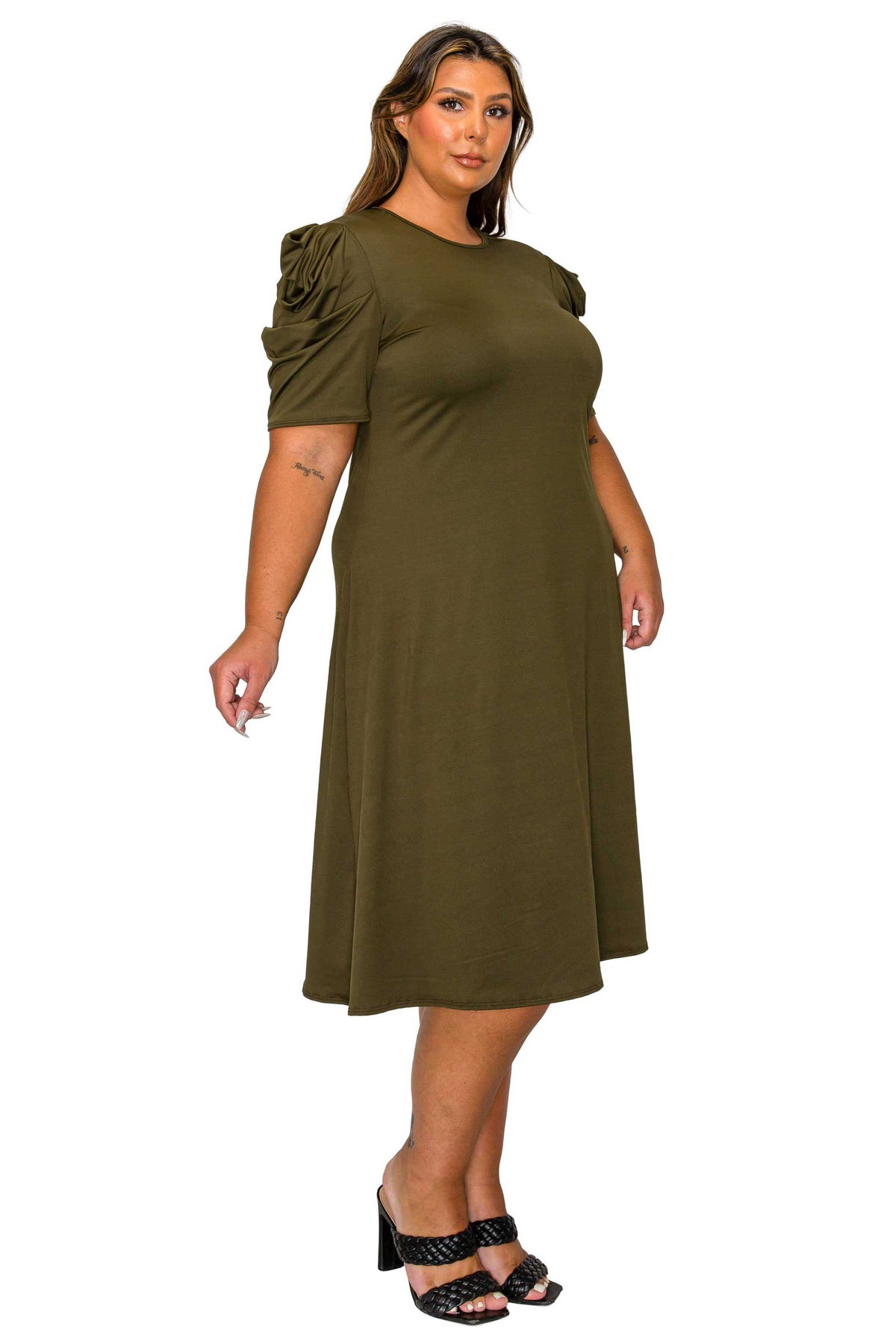 A woman modeling an olive green midi dress with short ruffled sleeves, standing against a plain white background.