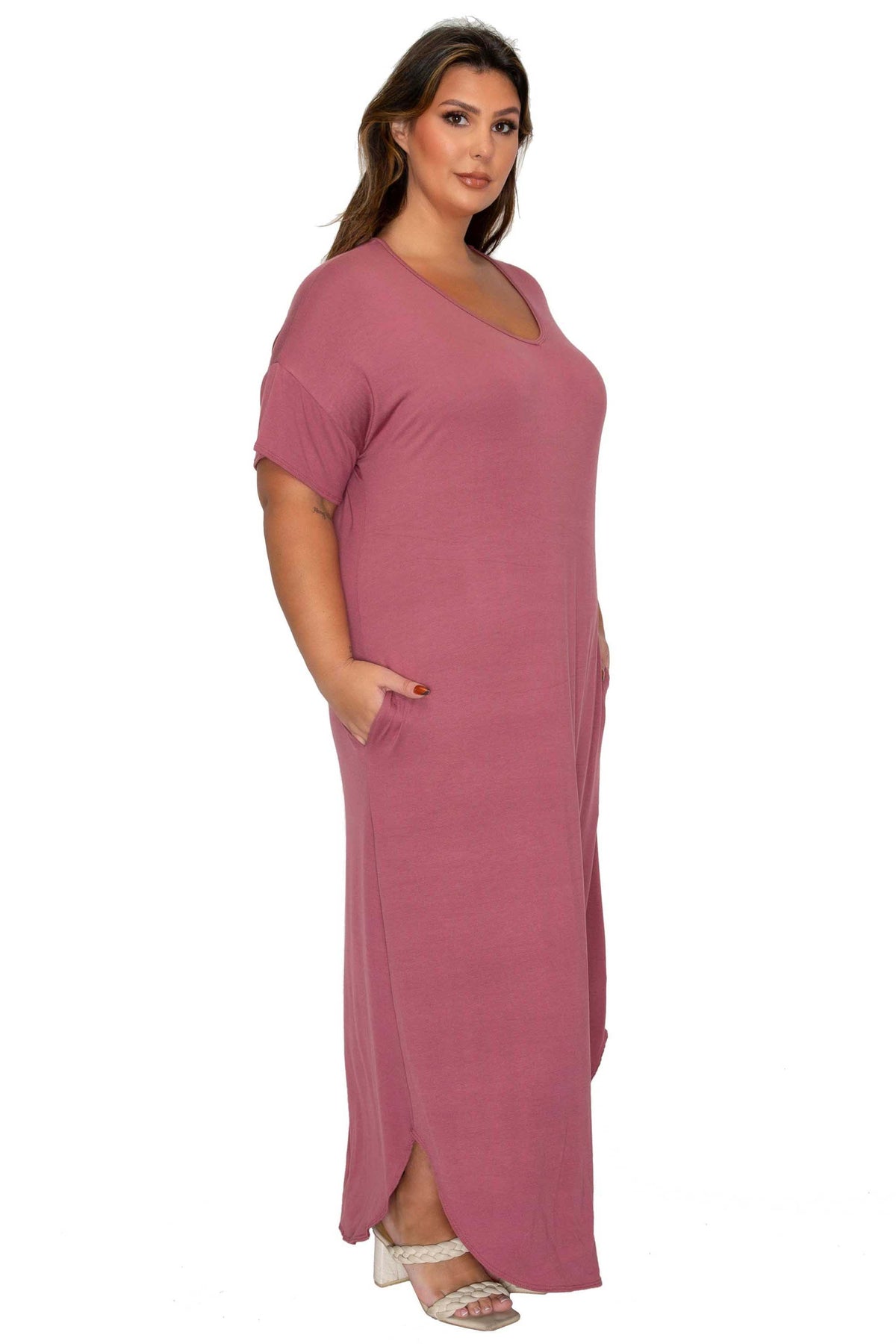 A woman modeling a dusty rose pink short-sleeve maxi dress with a V-neckline and side pockets, set against a plain white background.