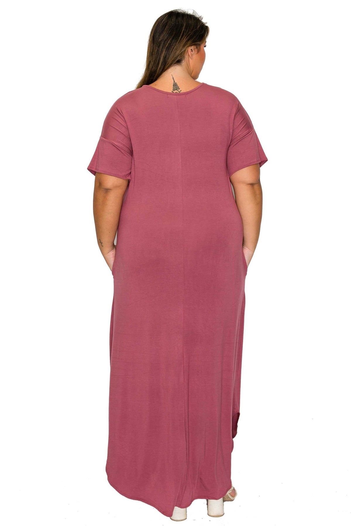 A woman viewed from the back wearing a dusty rose short-sleeve maxi dress with side pockets, set against a plain white background.