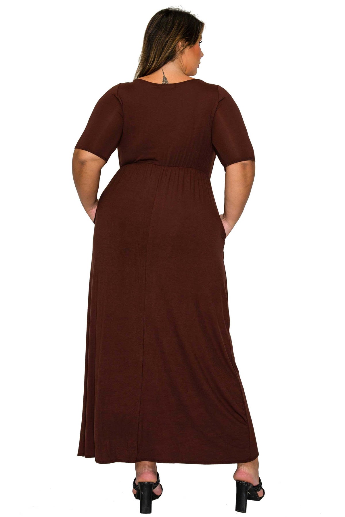 A woman shown from the back wearing a dark brown short-sleeve maxi dress with side pockets, paired with black high-heeled sandals, against a plain white background.
