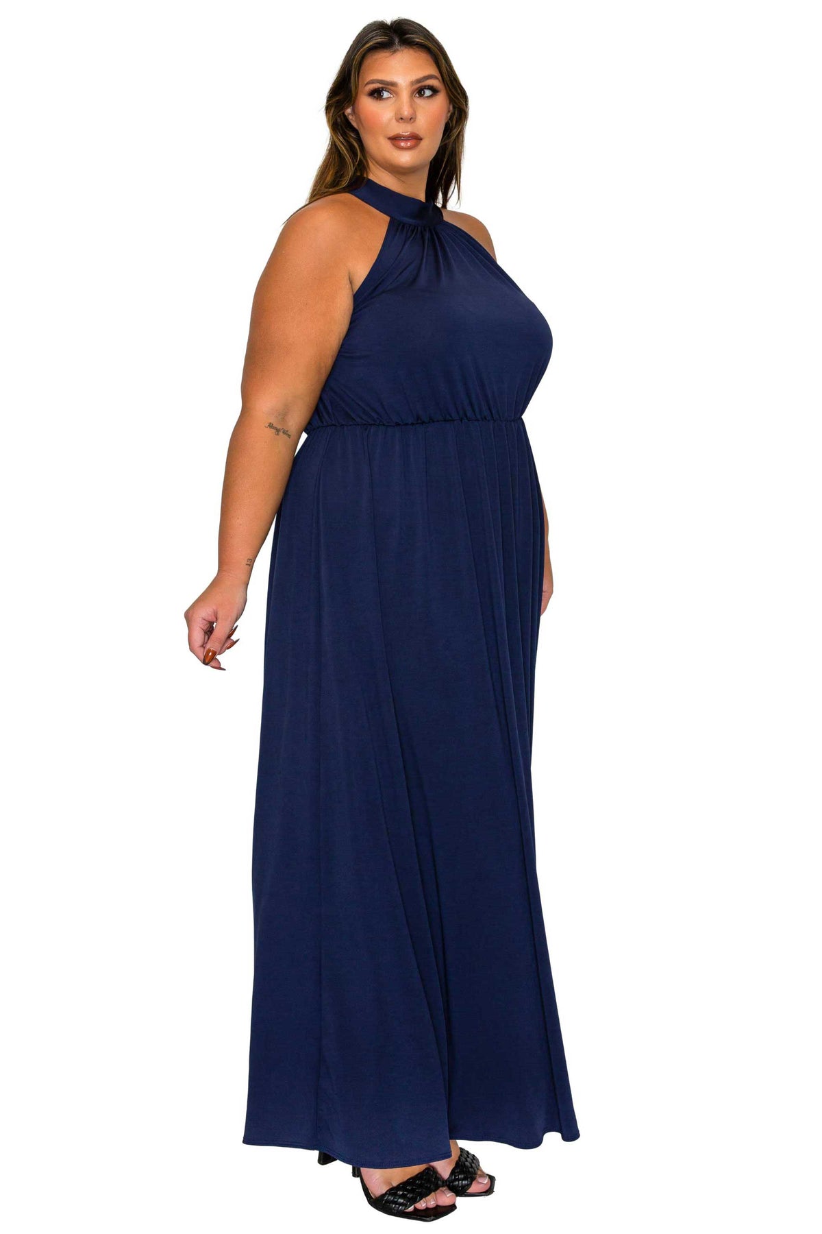 A woman modeling a navy blue halter-neck maxi dress with a gathered waist, shown against a plain white background.