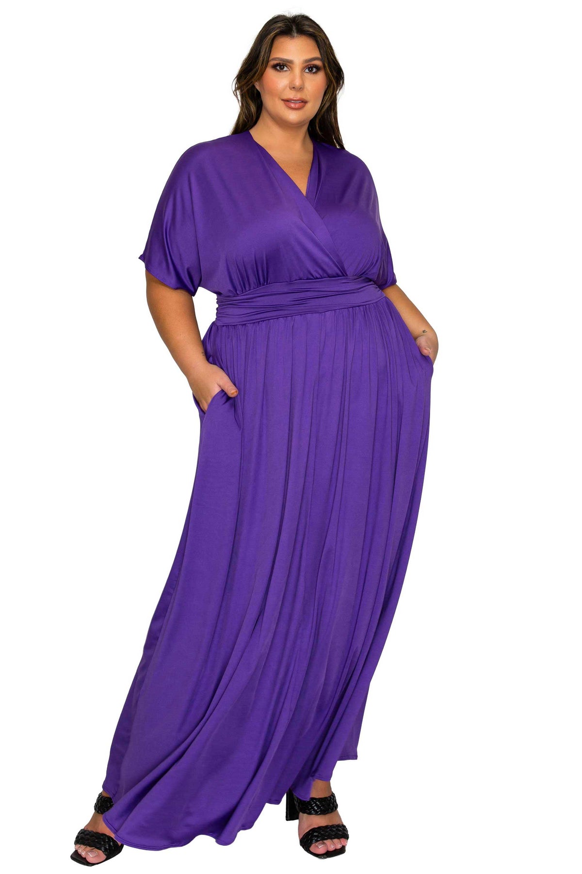 A woman modeling a purple wrap-style maxi dress with short sleeves, side pockets, and a self-tie waist belt, shown against a plain white background.