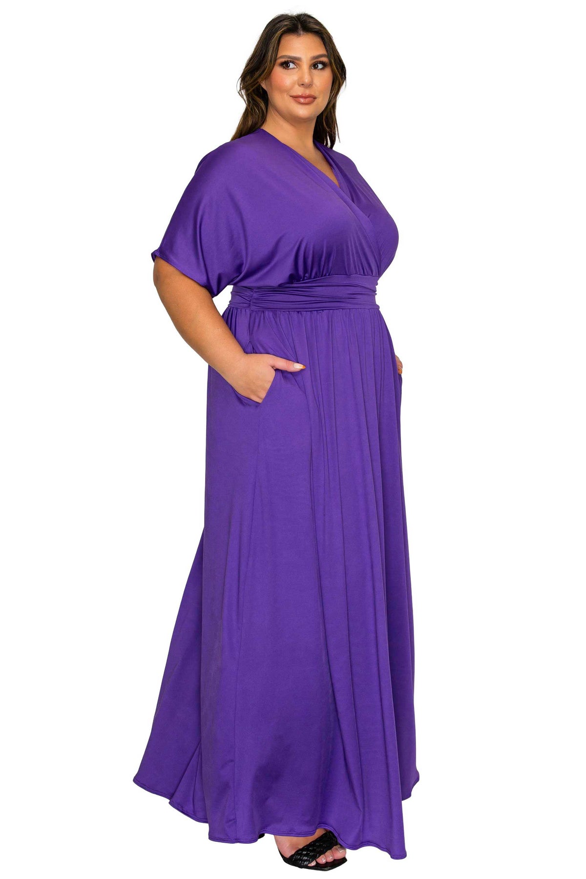 A woman modeling a purple maxi dress with short flutter sleeves, a V-neckline, and side pockets, shown against a plain white background.