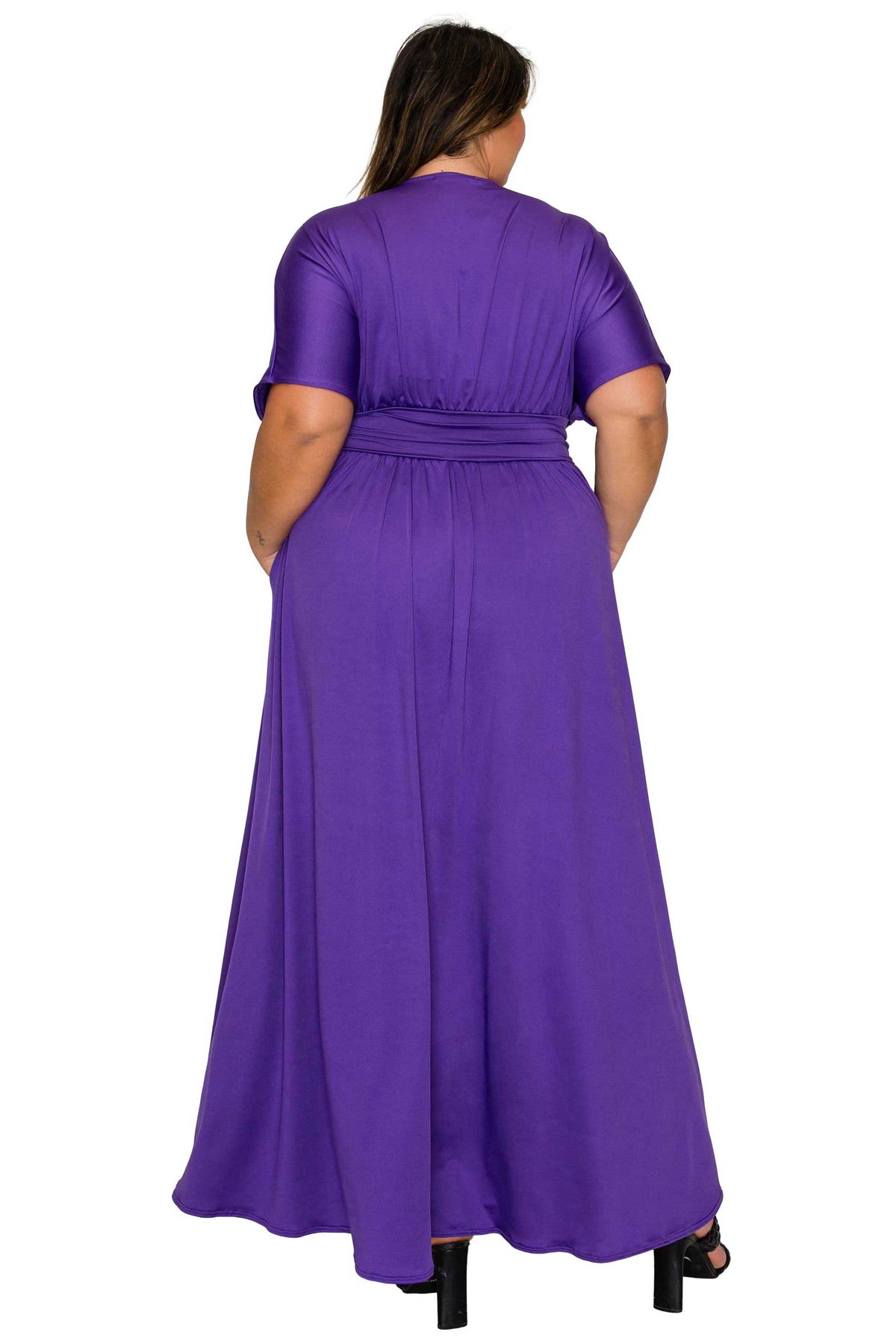 A woman viewed from the back wearing a purple short-sleeve maxi dress with a matching waist tie, set against a plain white background.