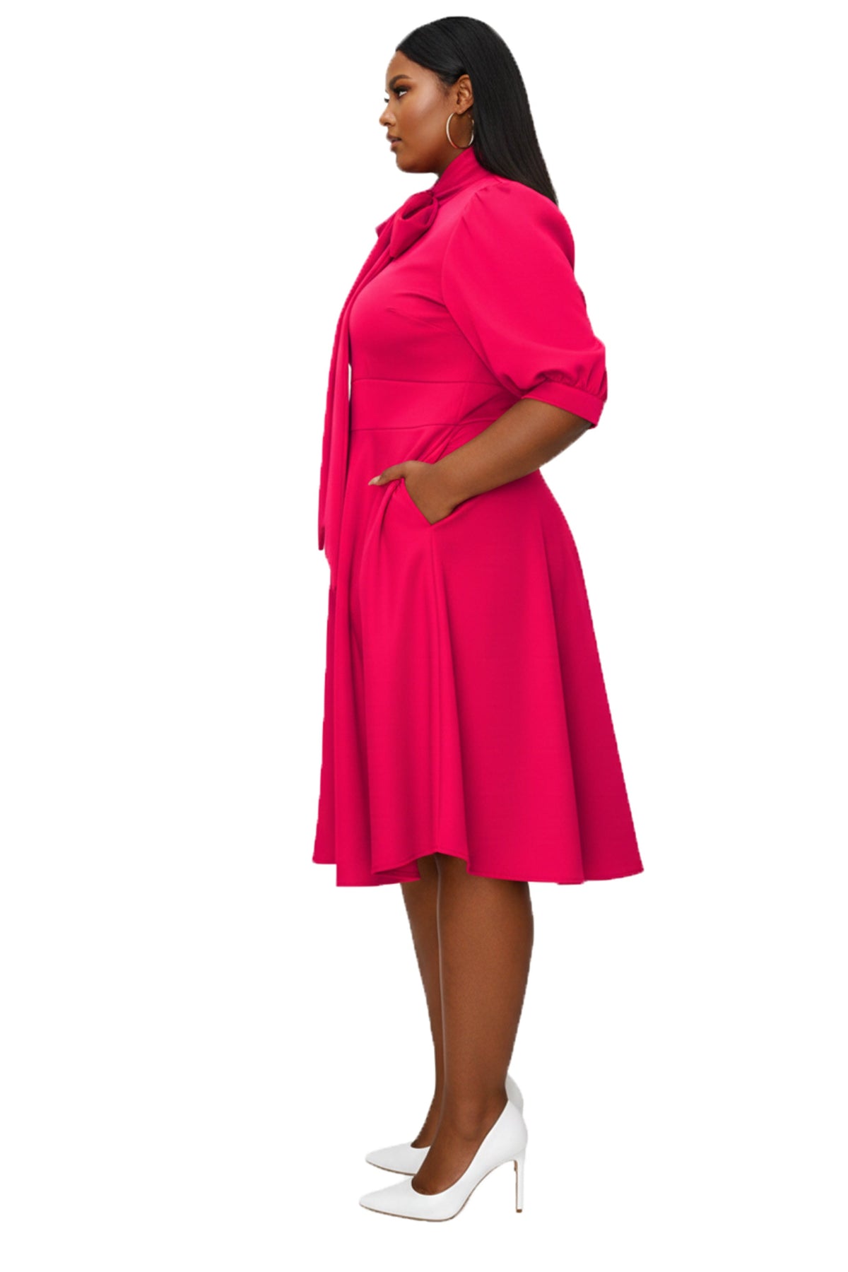 A woman modeling a bright pink midi dress with puff sleeves, a tie collar, and a flared skirt, shown in profile against a plain white background.
