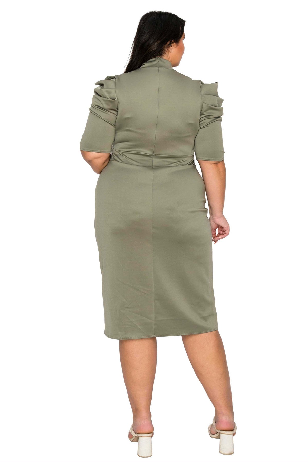 A woman viewed from the back wearing a knee-length sage green dress with ruffled short sleeves and structured shoulders, paired with white block-heel sandals, against a plain white background.