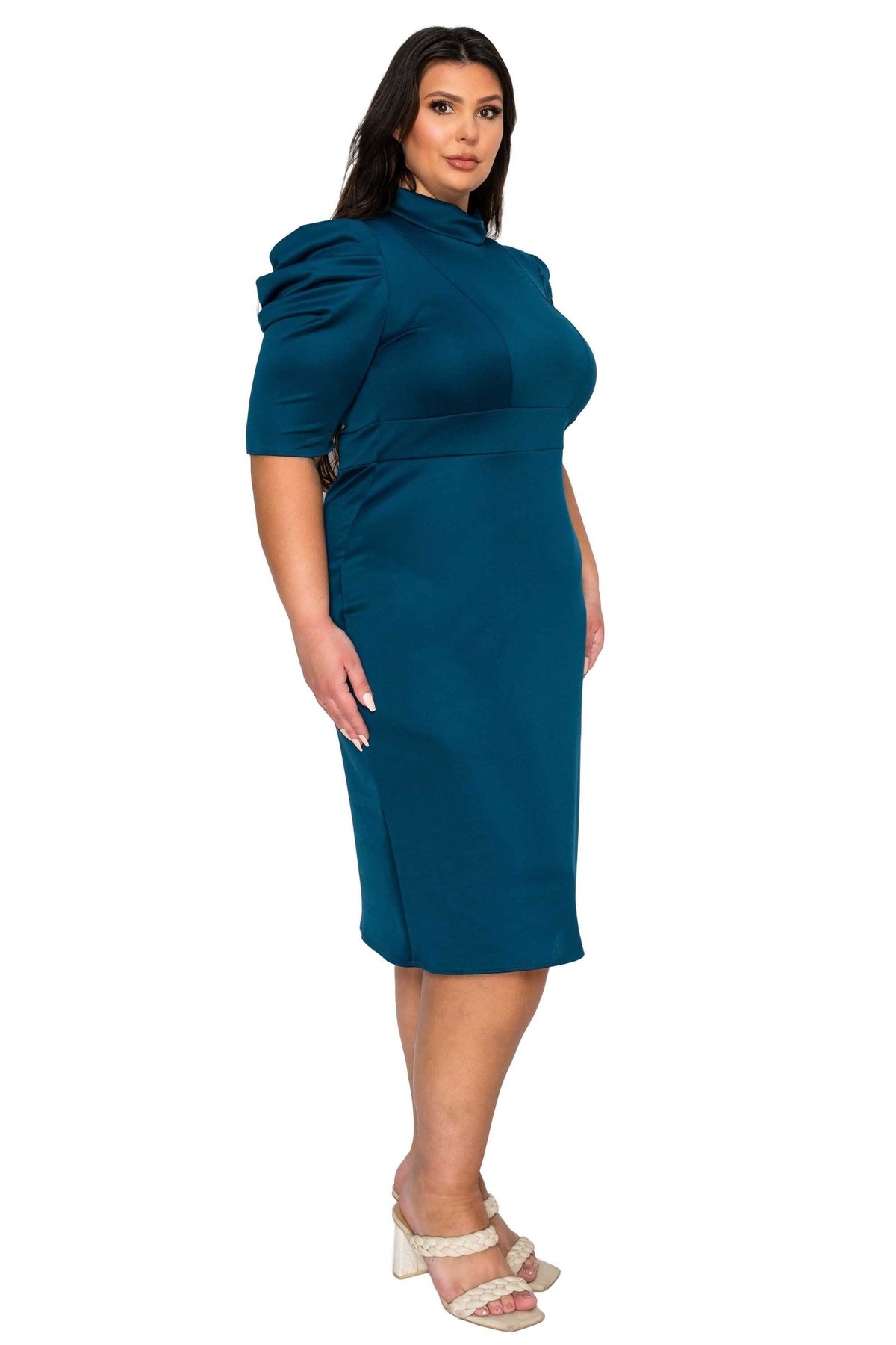 A woman modeling a teal blue midi dress with a high mock neck, short puff sleeves, and a fitted silhouette, paired with beige heeled sandals against a plain white background.