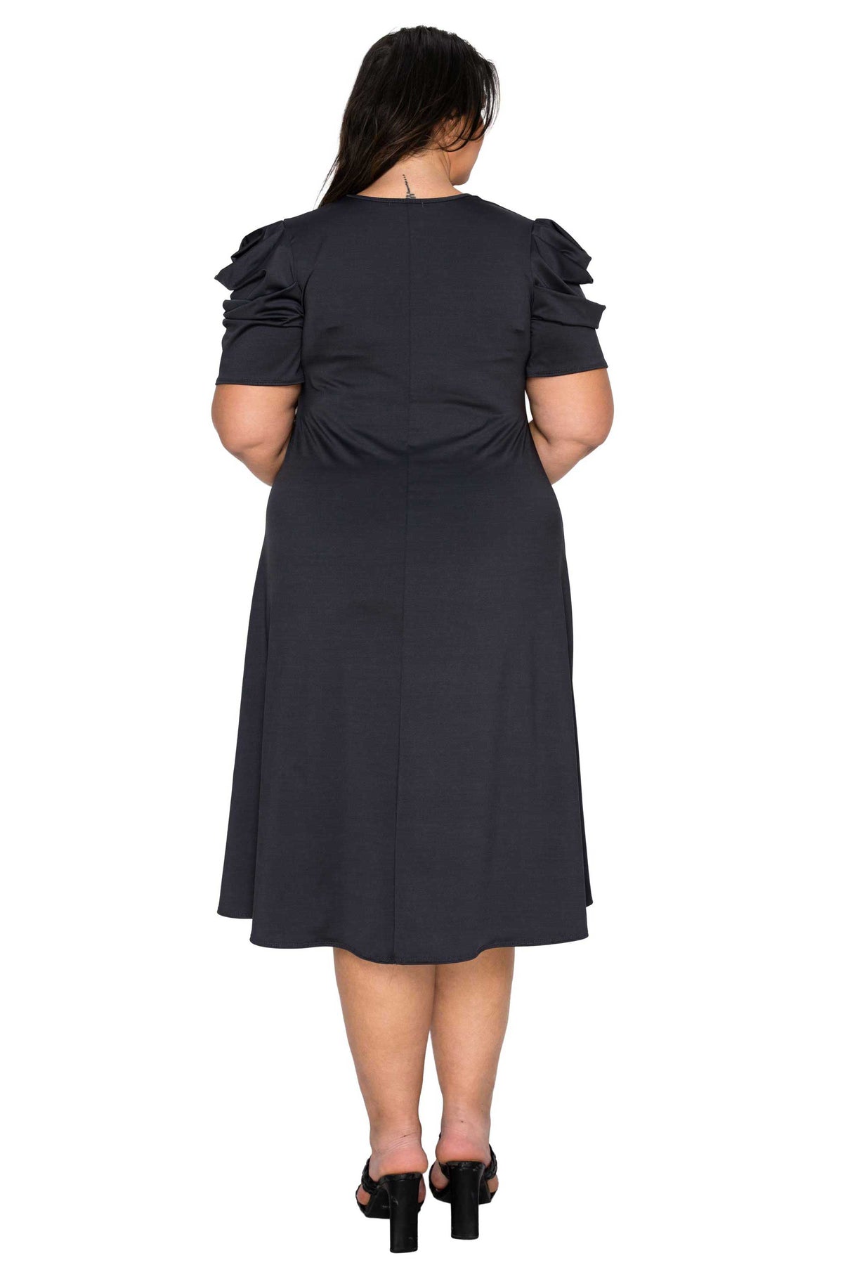 Black dress with puff sleeves worn by a model on a white background
