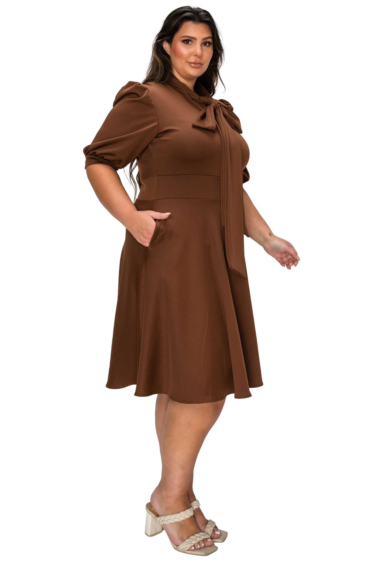 Woman wearing a brown dress with puff sleeves on a white background