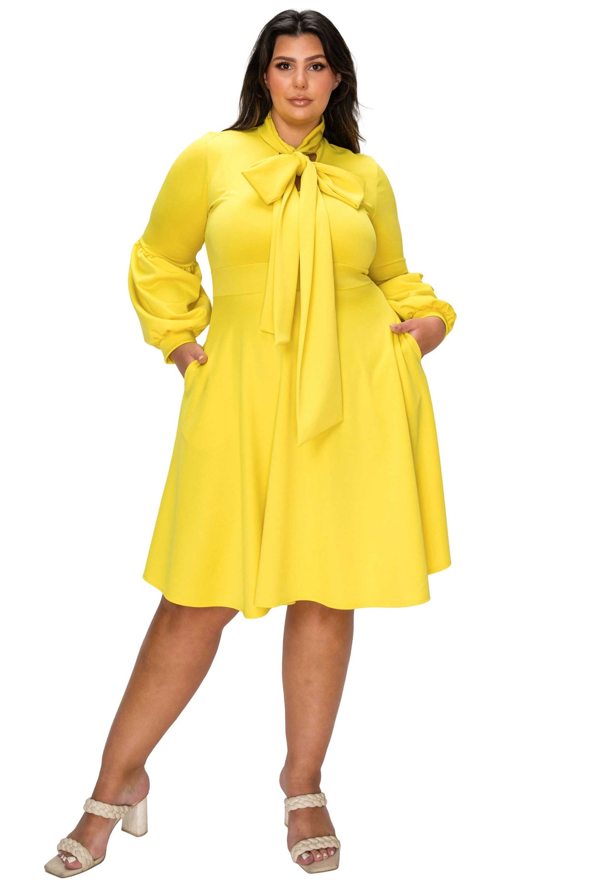 Woman wearing a yellow dress with a tie-neck design on a white background