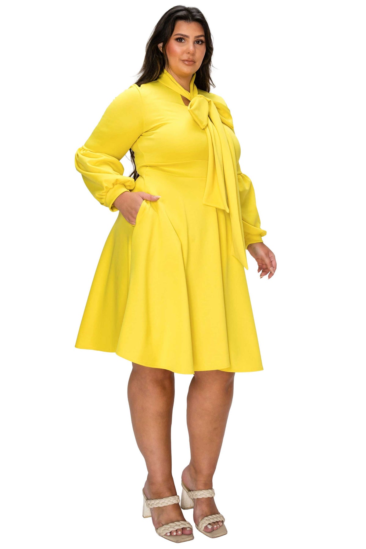 Woman wearing a yellow dress with a tie waist on a white background