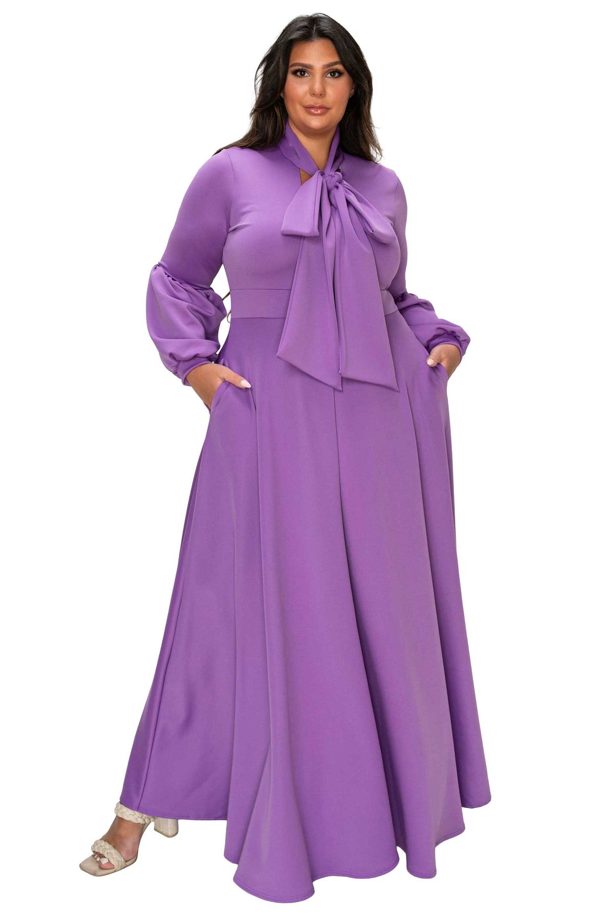 Woman wearing a long purple dress with a bow tie on a white background