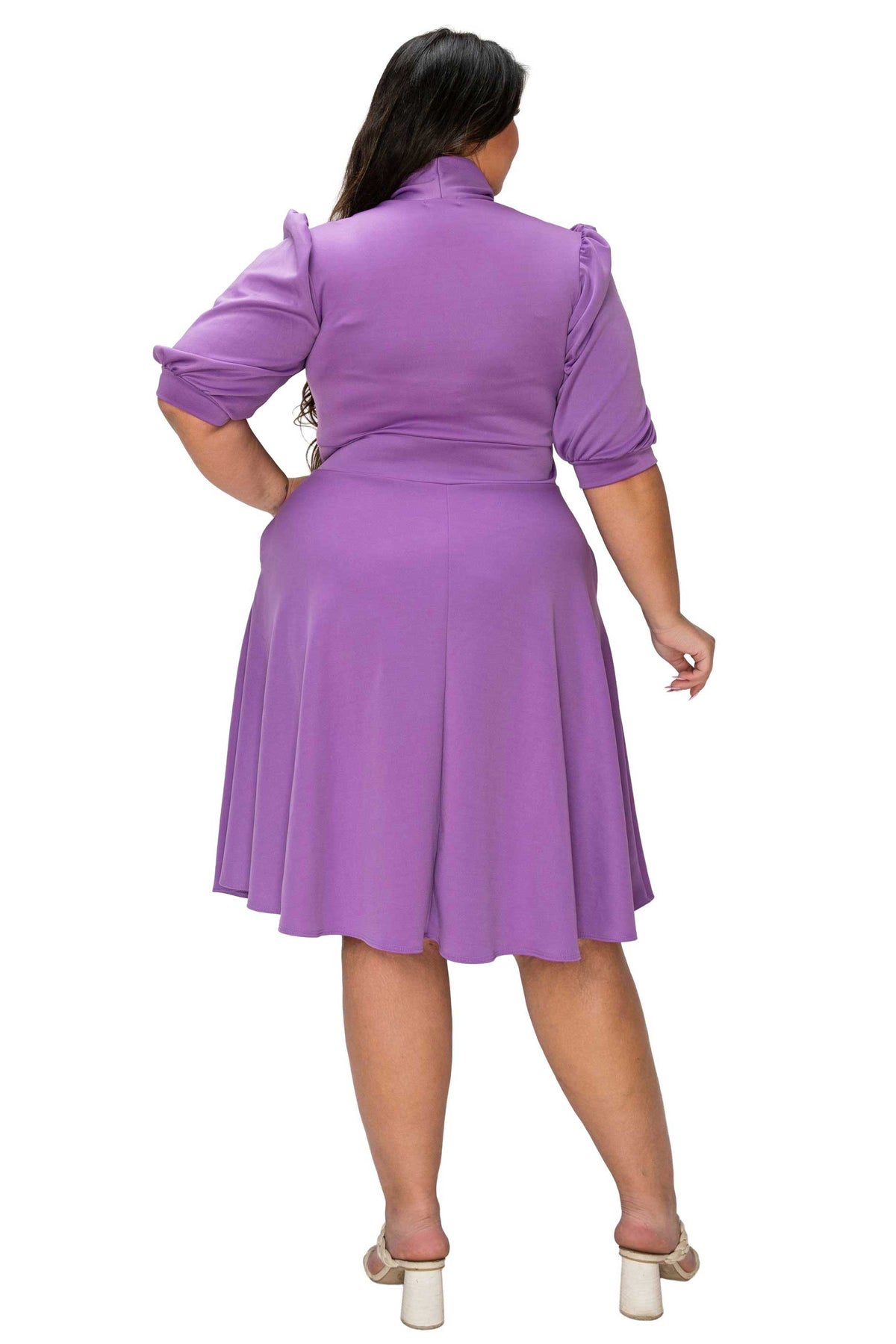 Woman wearing a purple dress with puff sleeves on a white background
