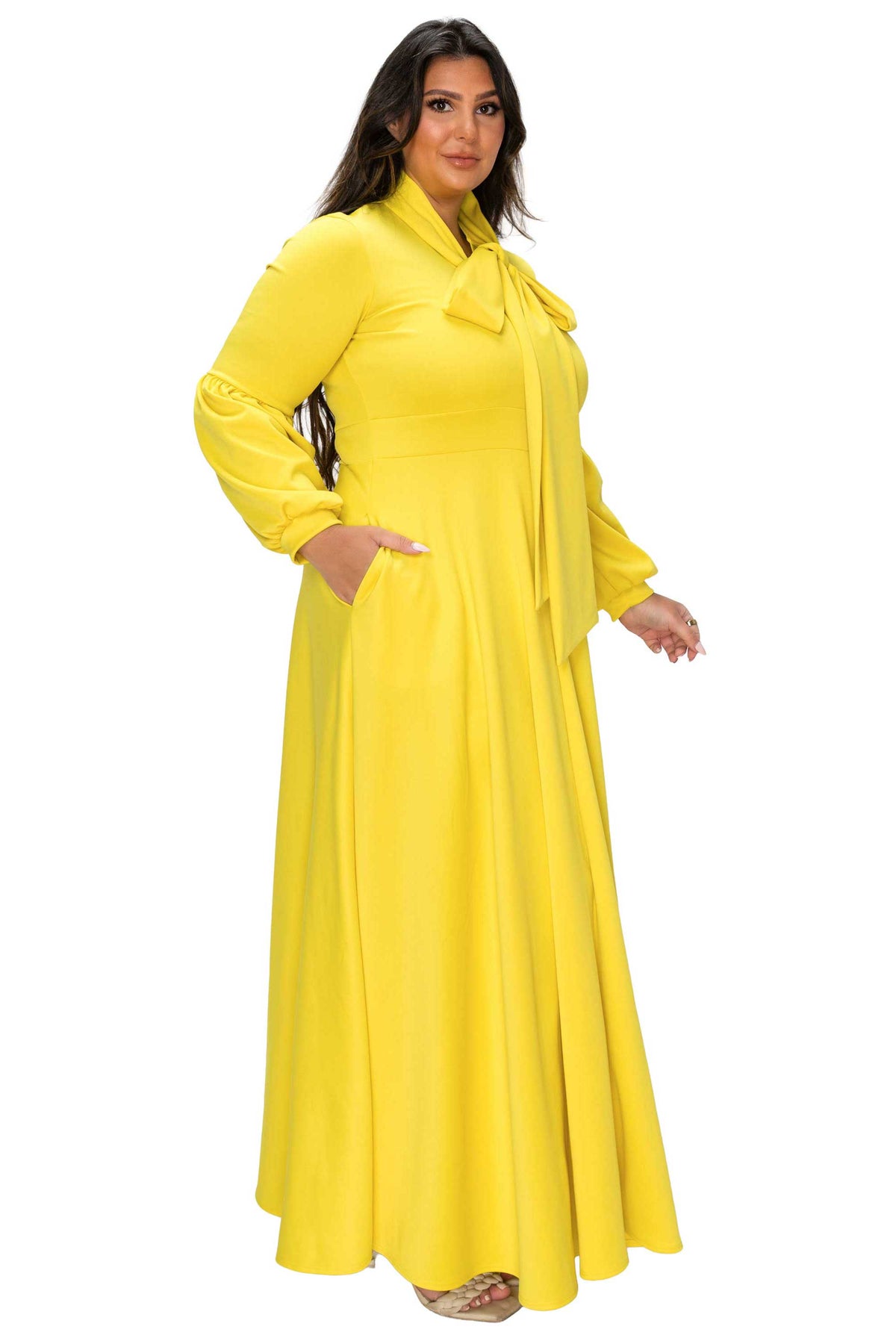 Woman wearing a yellow long-sleeve dress with a bow detail on a white background