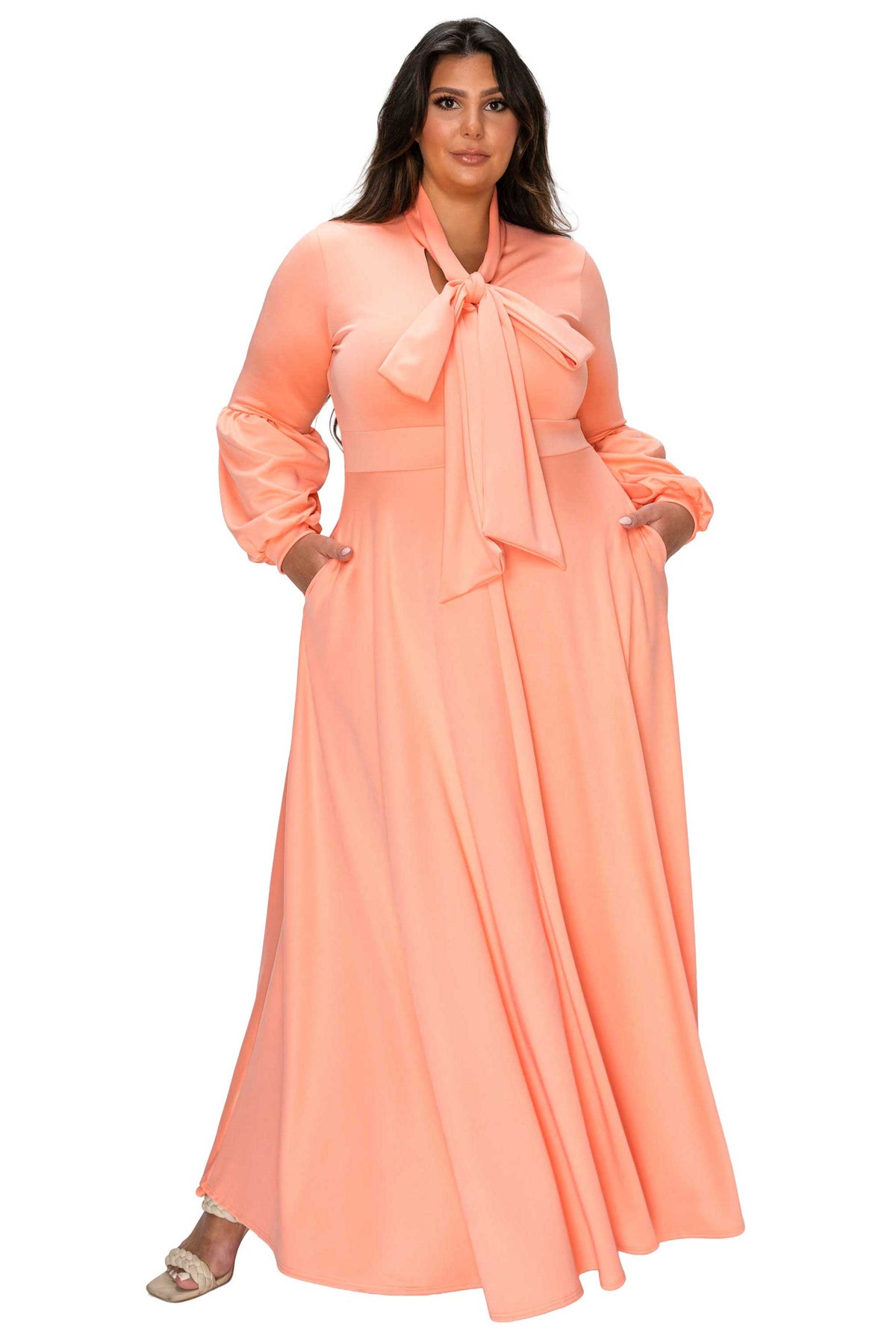 Woman wearing a peach-colored dress with a large bow on a white background