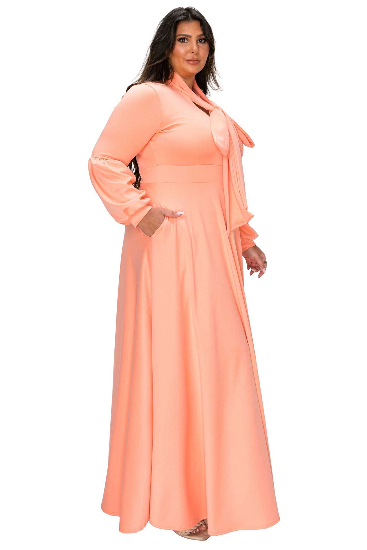 Woman wearing a peach long dress with a matching jacket on a white background