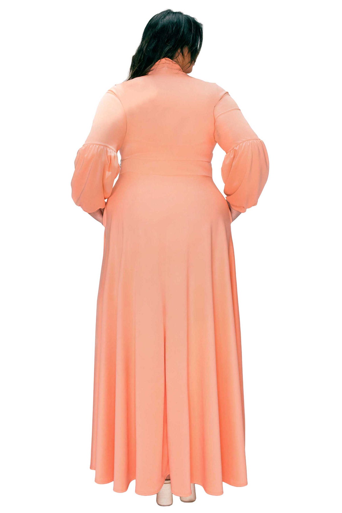Person wearing a peach-colored dress with puffed sleeves on a white background