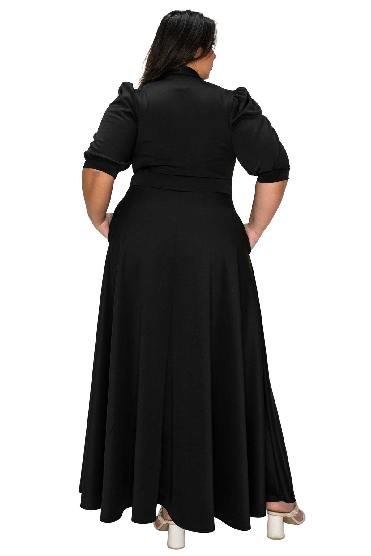 Woman wearing a black dress with puffed sleeves from behind on a white background