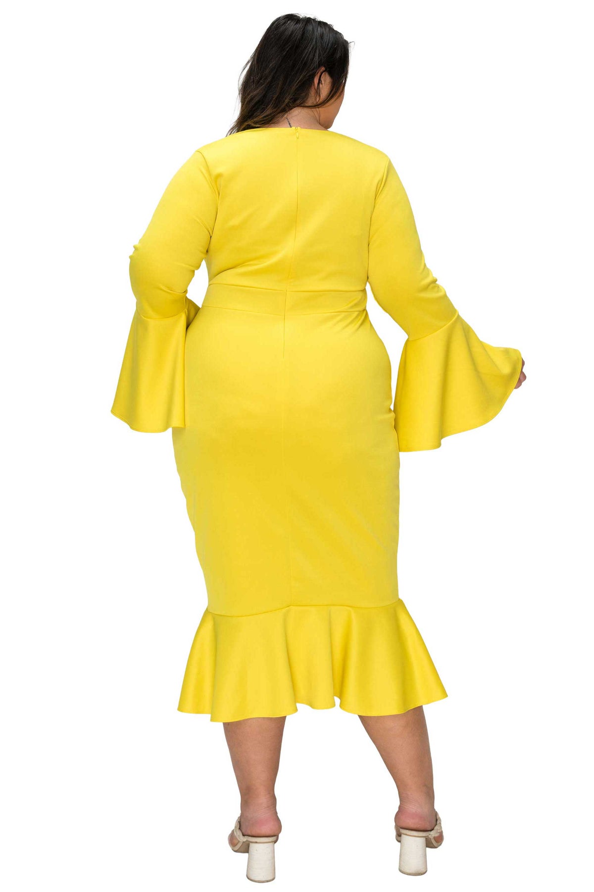 Woman wearing a yellow dress with flared sleeves on a white background