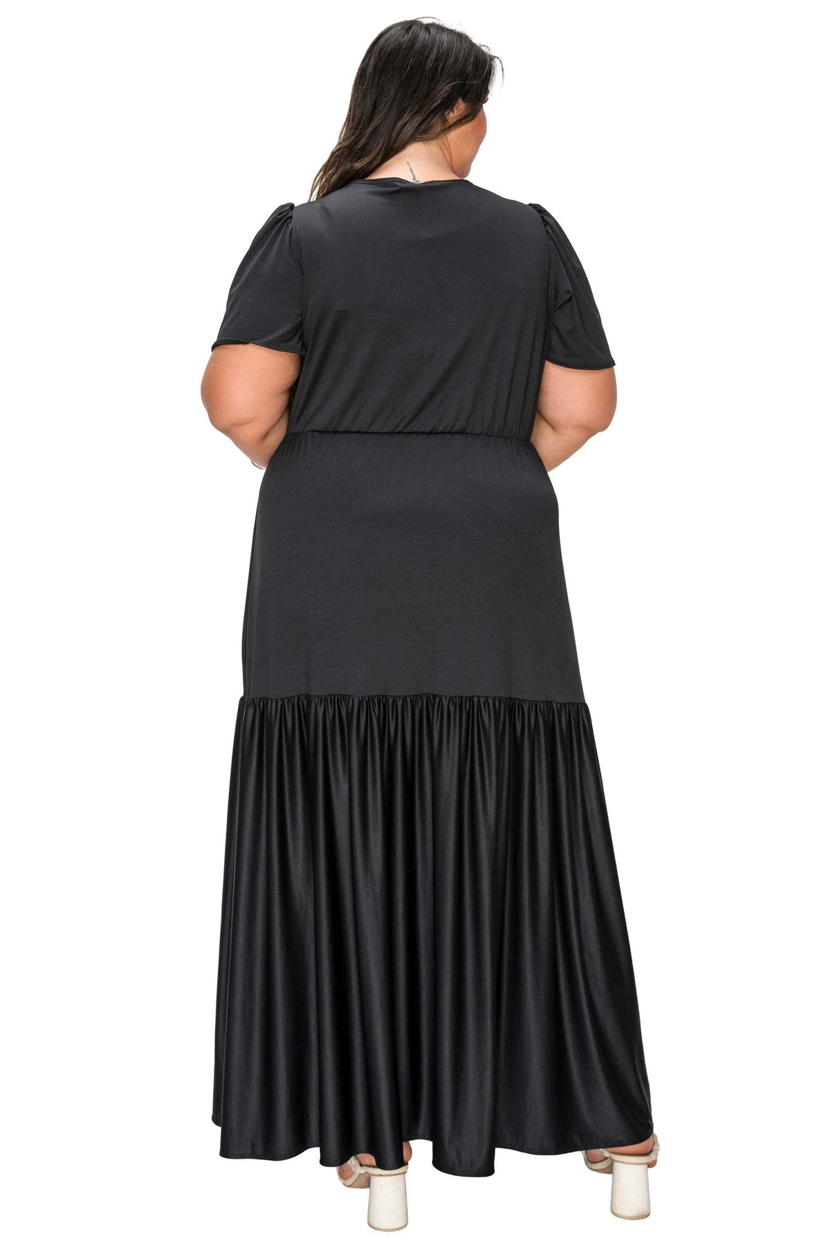 Black dress with a tiered skirt worn by a person on a white background