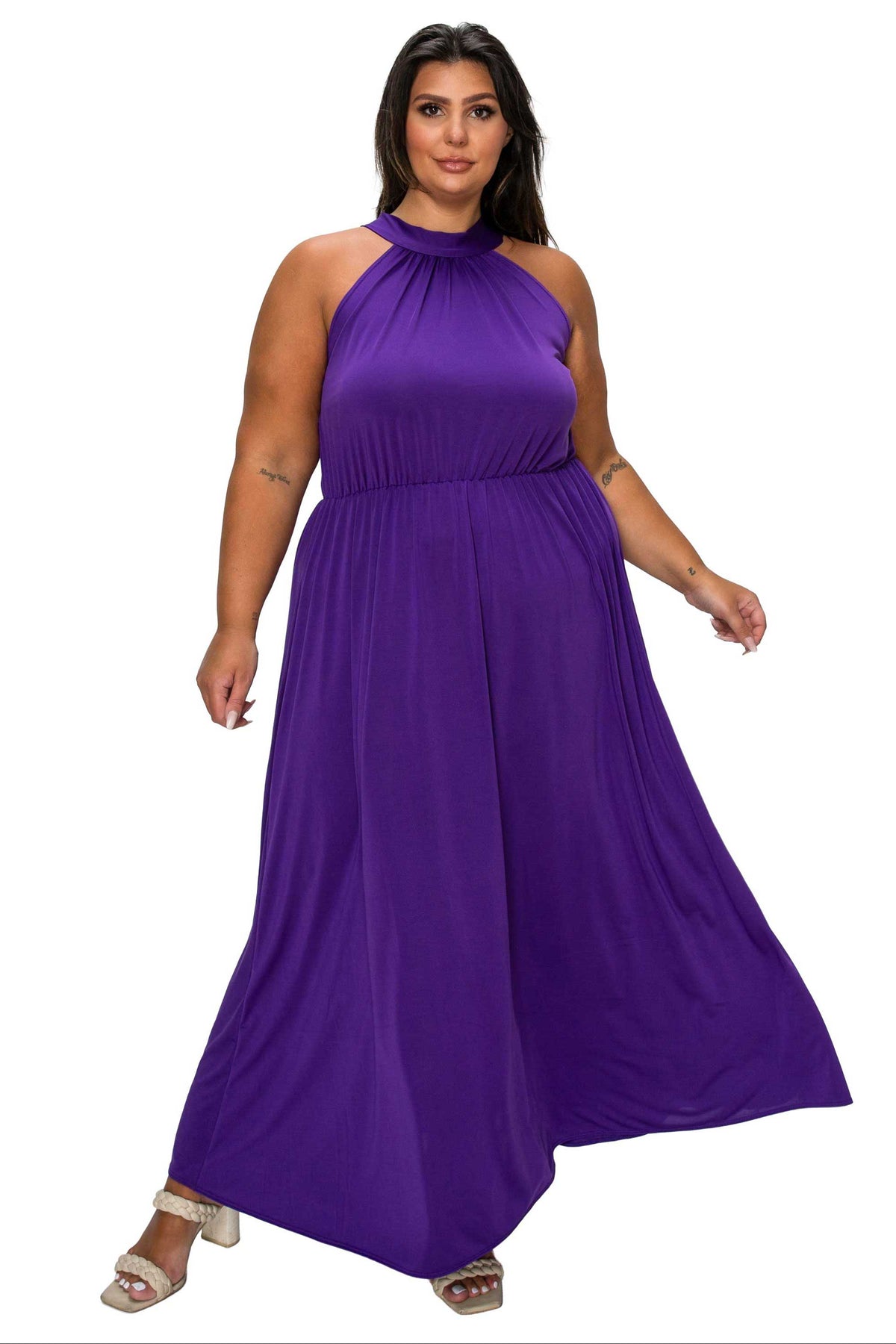 A woman modeling a sleeveless, high-neck, floor-length purple maxi dress against a plain white background.