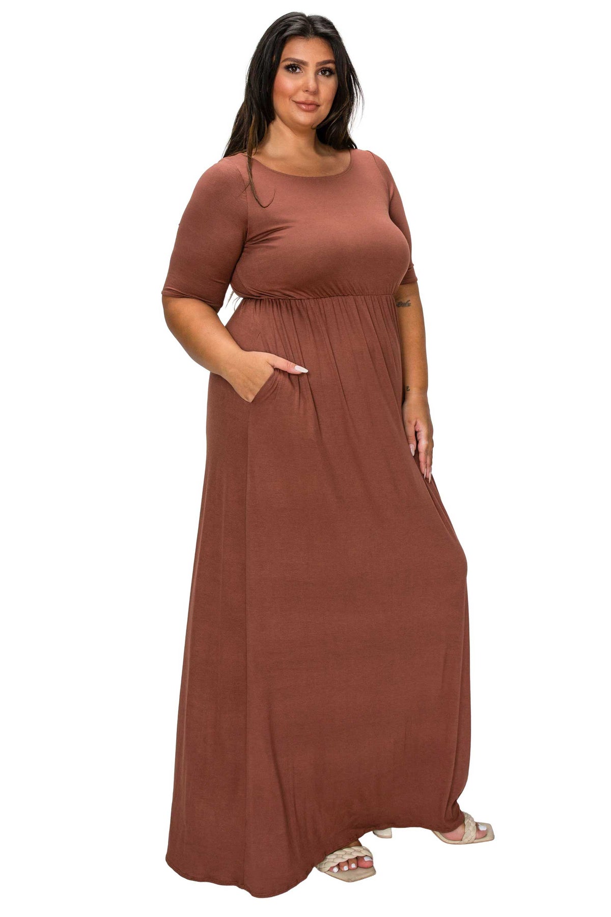 A woman modeling a rust-brown maxi dress with short sleeves, a round neckline, and side pockets, set against a plain white background.