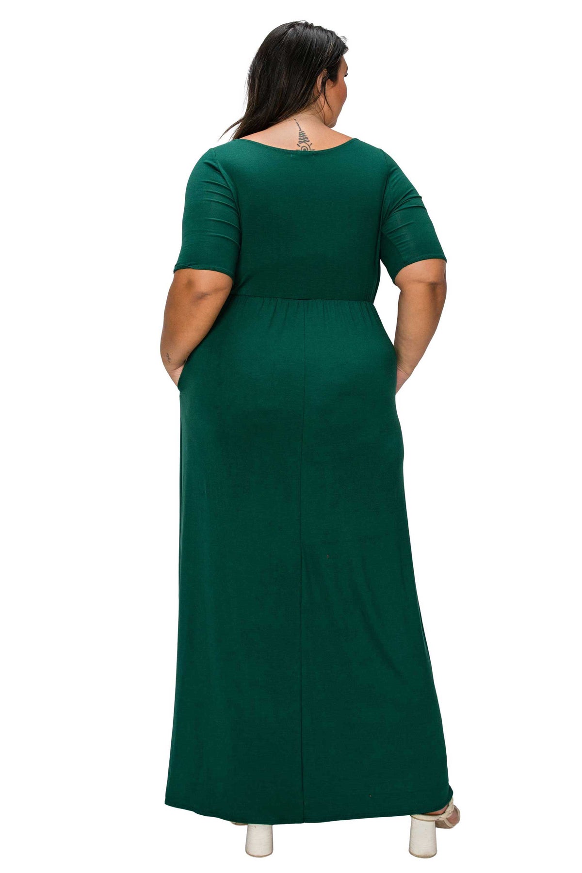 A woman viewed from the back wearing a dark green short-sleeve maxi dress with side pockets, set against a plain white background.